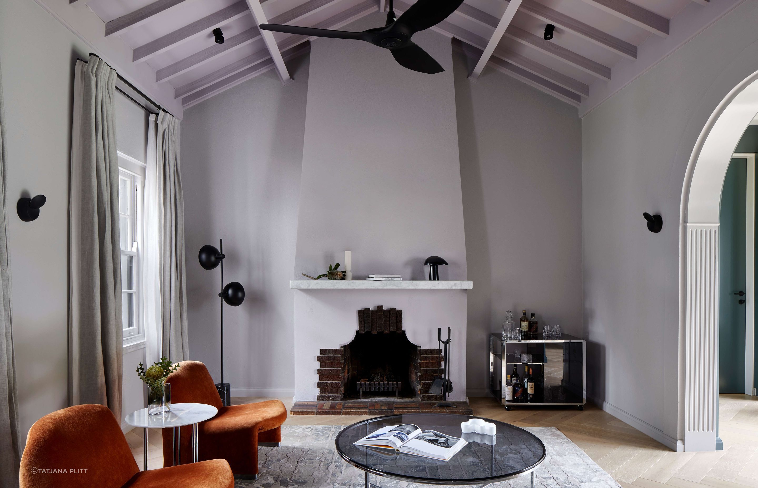 Living room with central 1930’s Art Deco original fireplace and vaulted ceiling painted in violet from Dulux. Flooring is oak with a matt lacquer to draw in the art deco heritage of the home. The room is furnished with Elke paprika velvet chairs from Castelli, and the Willy Rizzo Bar cart from Castorina. See more from our Arch Deco Project.