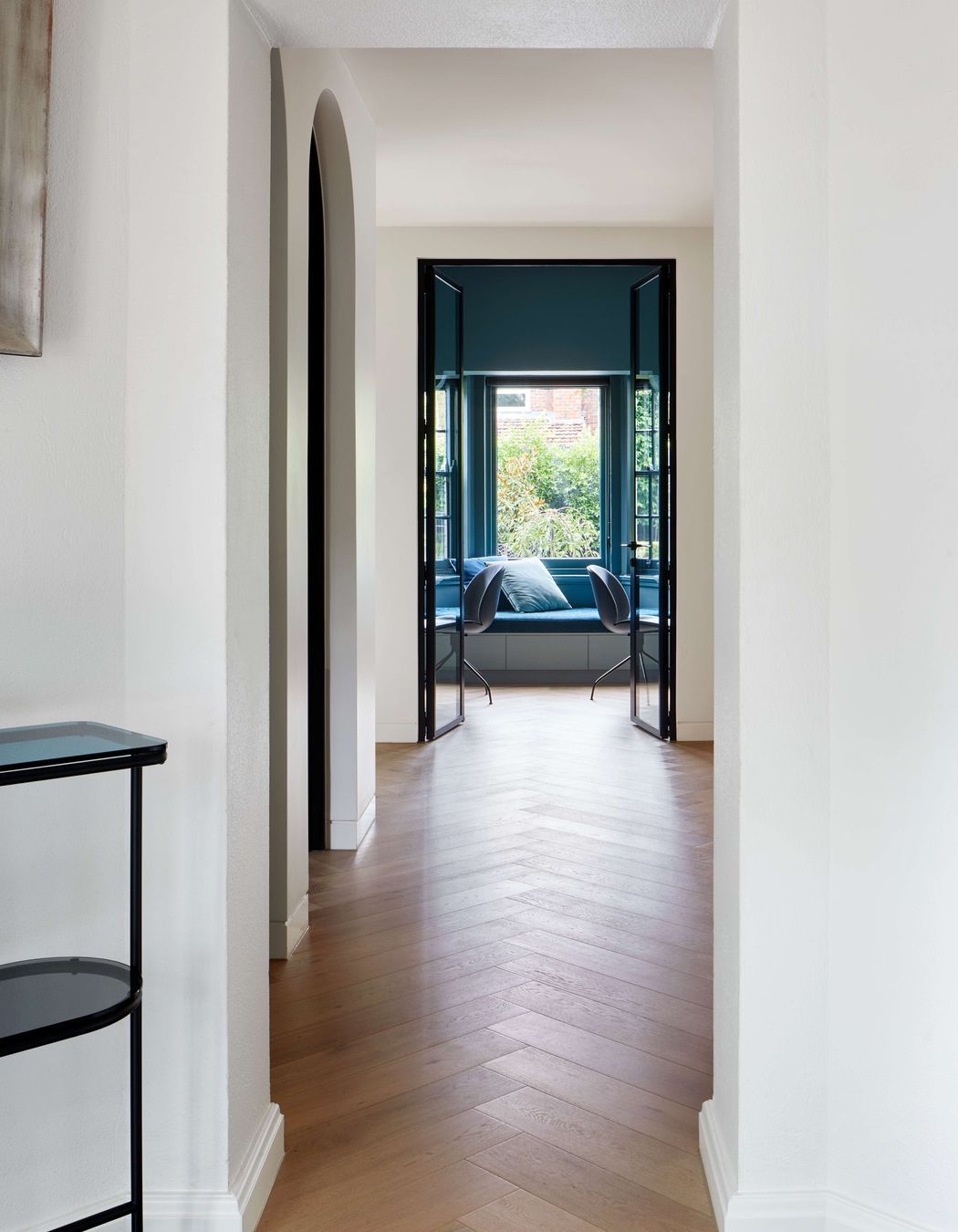 Hallway looking through to study featuring flooring is oak wood herringbone, as the central corridor to living and kitchen areas in this 1930s art deco renovation in Melbourne. See more from our Arch Deco Project.