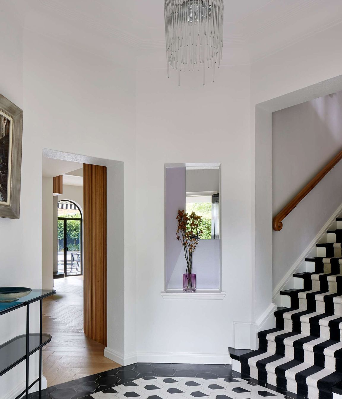 Large black and white art deco entryway with geometric concrete matt tiling from Perini, matched with black and white stairway carpet runner. The project is a 1930s art deco spanish mission style house in Melbourne. See more from our Arch Deco Project.