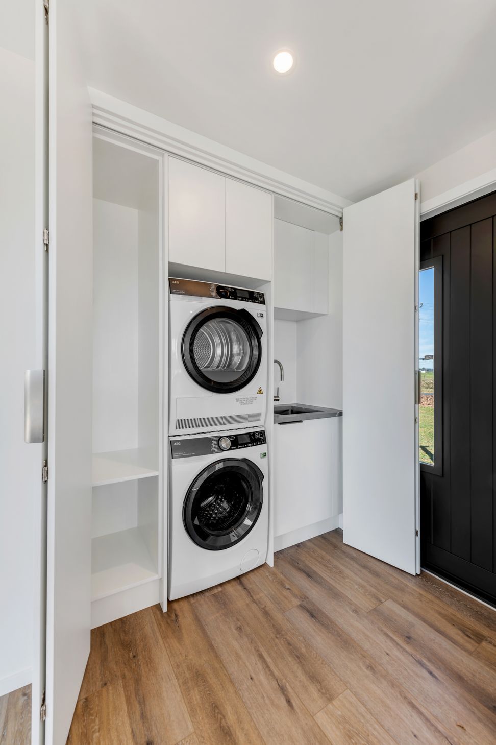 “One of my favourite little details.”  - We tucked a full laundry into this cabinet—stacked washer-dryer, overhead storage, all out of sight but easy to get to.