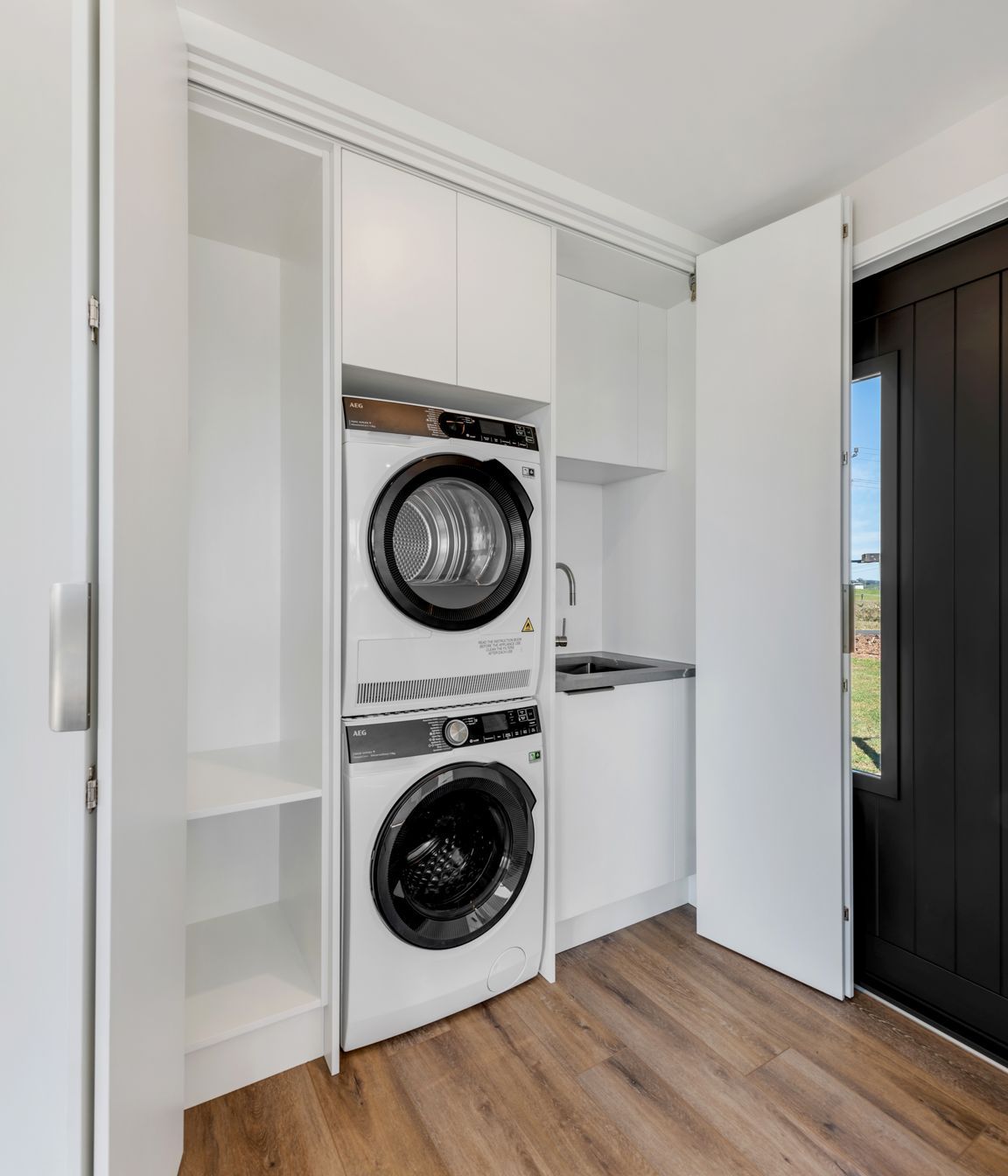“One of my favourite little details.”  - We tucked a full laundry into this cabinet—stacked washer-dryer, overhead storage, all out of sight but easy to get to.