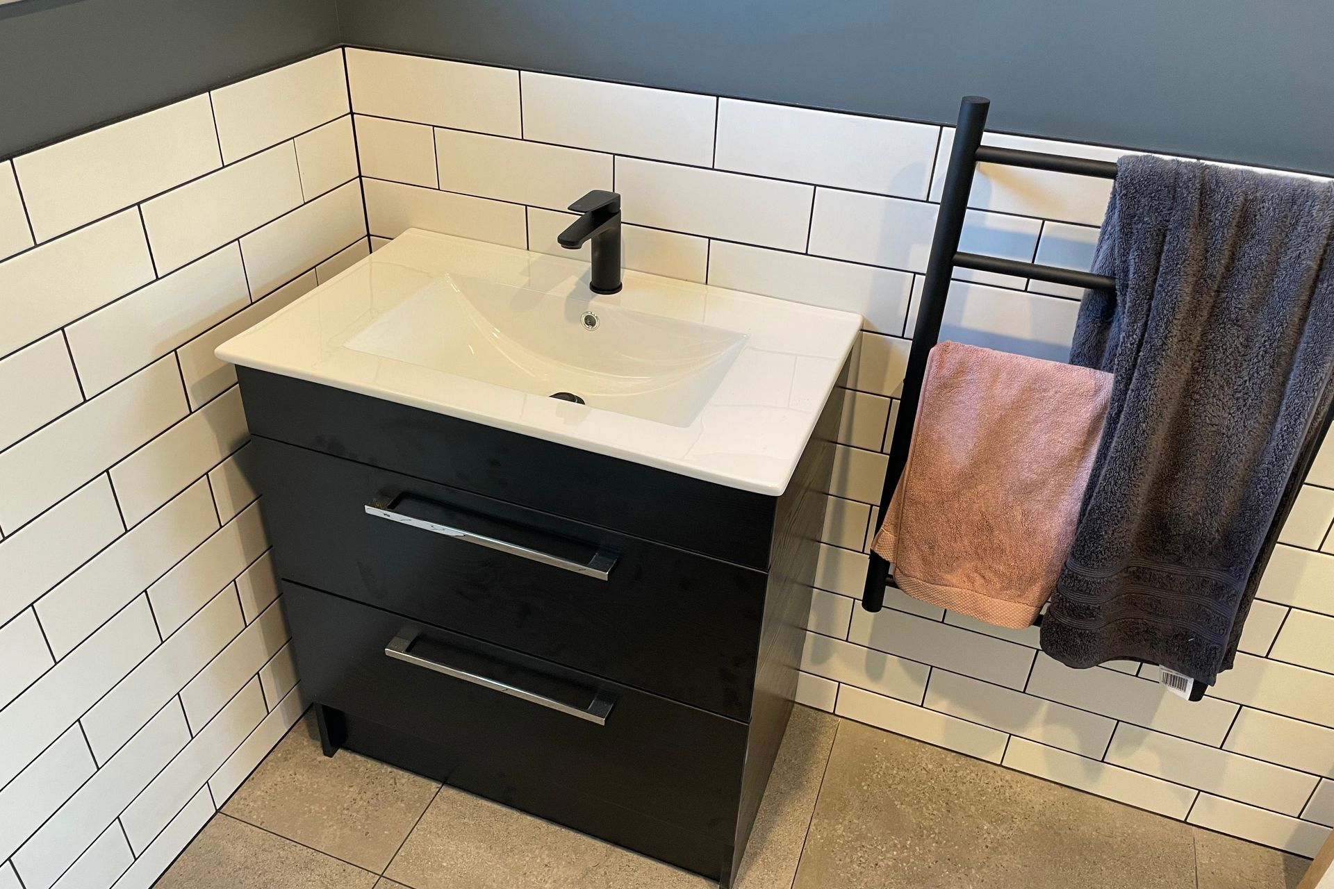 Black and white vanity with matching tiles and towel rail.