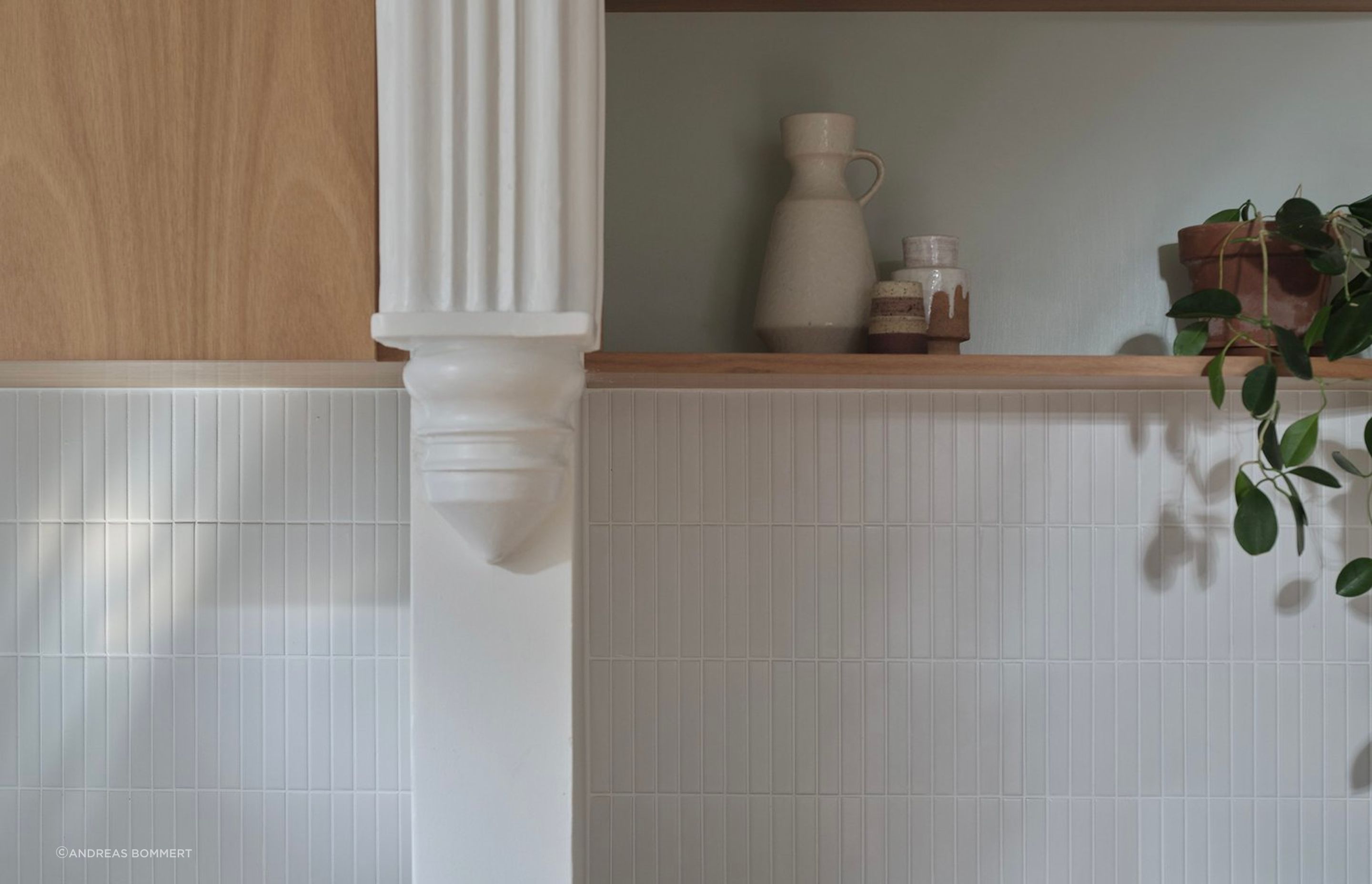 Top cupboards housing the rangehood intersect the kitchen’s dividing wall and continue as open display shelving in the dining room for extra storage and visual balance.