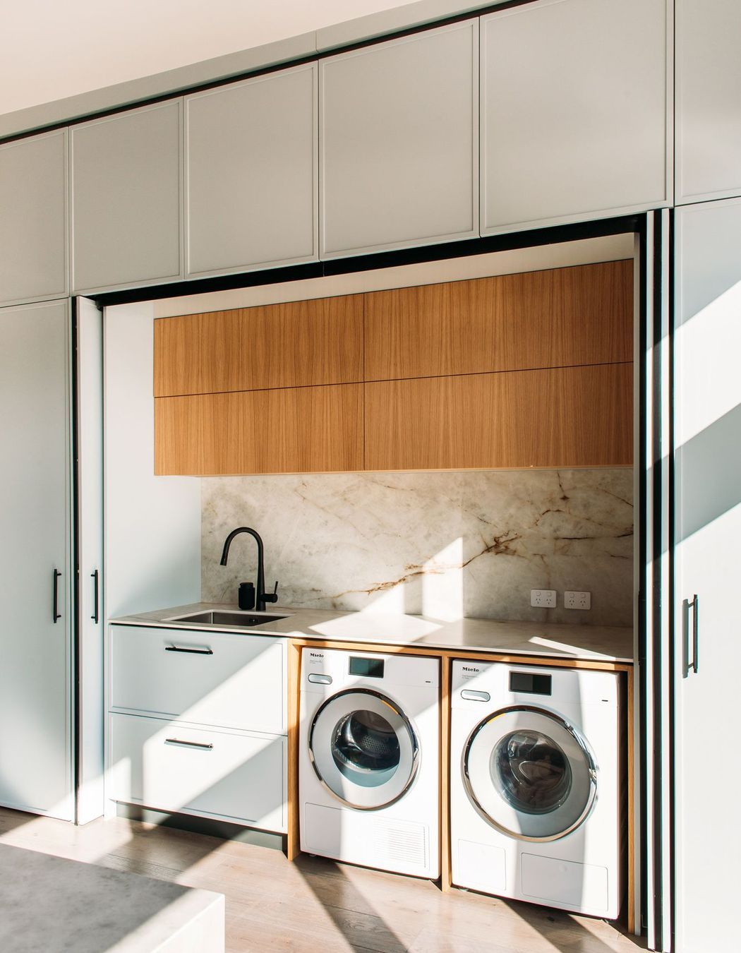 The laundry sits adjacent to the kitchen and the back door. And doubles as a scullery space with second sink and extra storage.