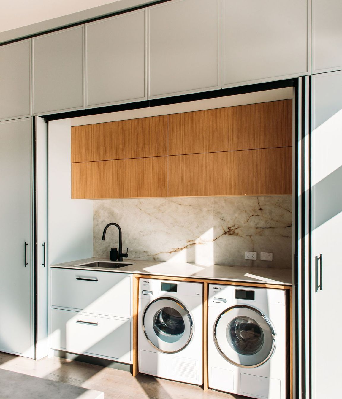 The laundry sits adjacent to the kitchen and the back door. And doubles as a scullery space with second sink and extra storage.
