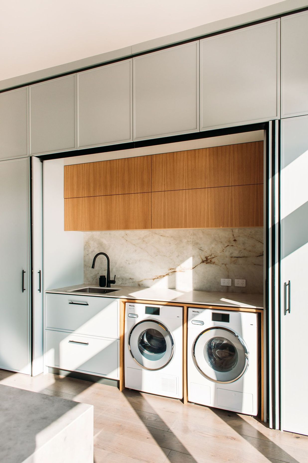 The laundry sits adjacent to the kitchen and the back door. And doubles as a scullery space with second sink and extra storage.