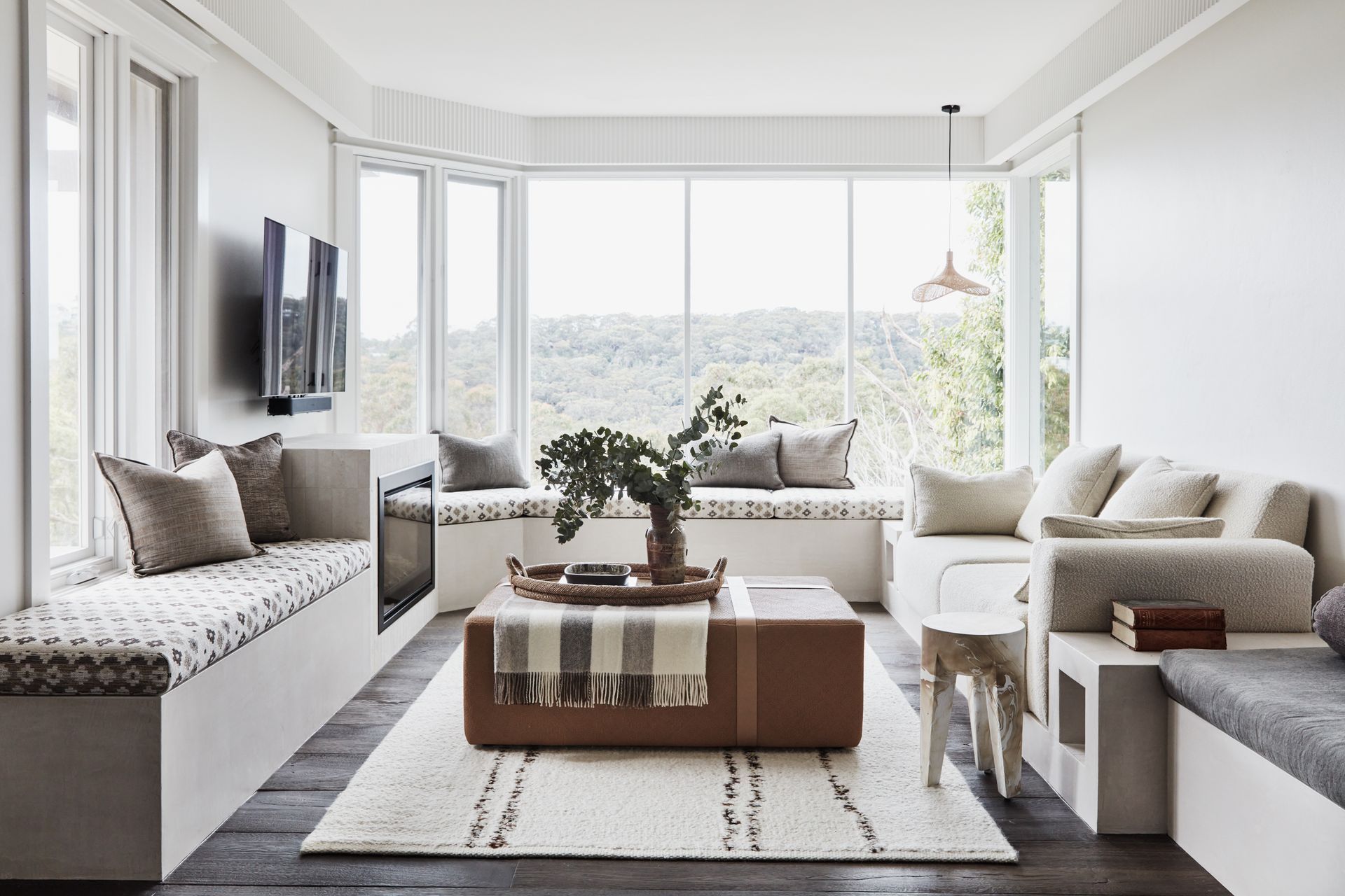 FAMILY ROOM A banquette lining three walls sets the tone in this informal sitting area with a view. Joinery in Natural White Micro-Cement, Idea Creations. The DF960 fireplace, from Escea, sits in a surround in raw-sawn limestone tiles, Onsite Supply+Design. Window seat covered in Schumacher ‘Ayumi Natural’ fabric, Orient House. Sofa covered in Alhambra ‘Ikaria Samos’ fabric, Elliott Clarke. Straw Hat pendant, Beautiful Halo. Fluted pelmet, Scandinavian Profiles. Custom ottoman. Resin stool, Made Goods. Indian Terra rug, Cadrys.