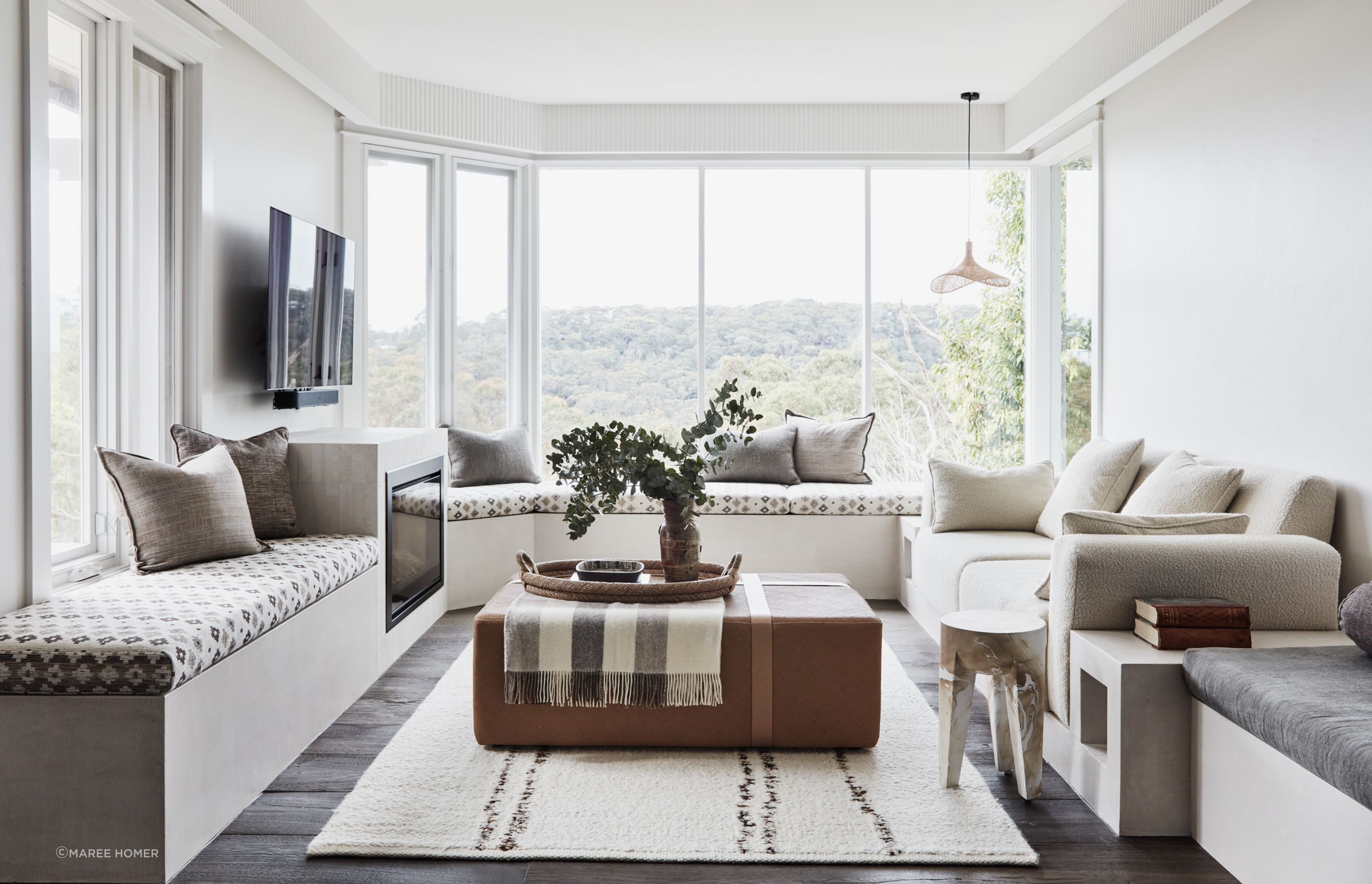FAMILY ROOM A banquette lining three walls sets the tone in this informal sitting area with a view. Joinery in Natural White Micro-Cement, Idea Creations. The DF960 fireplace, from Escea, sits in a surround in raw-sawn limestone tiles, Onsite Supply+Design. Window seat covered in Schumacher ‘Ayumi Natural’ fabric, Orient House. Sofa covered in Alhambra ‘Ikaria Samos’ fabric, Elliott Clarke. Straw Hat pendant, Beautiful Halo. Fluted pelmet, Scandinavian Profiles. Custom ottoman. Resin stool, Made Goods. Indian Terra rug, Cadrys.