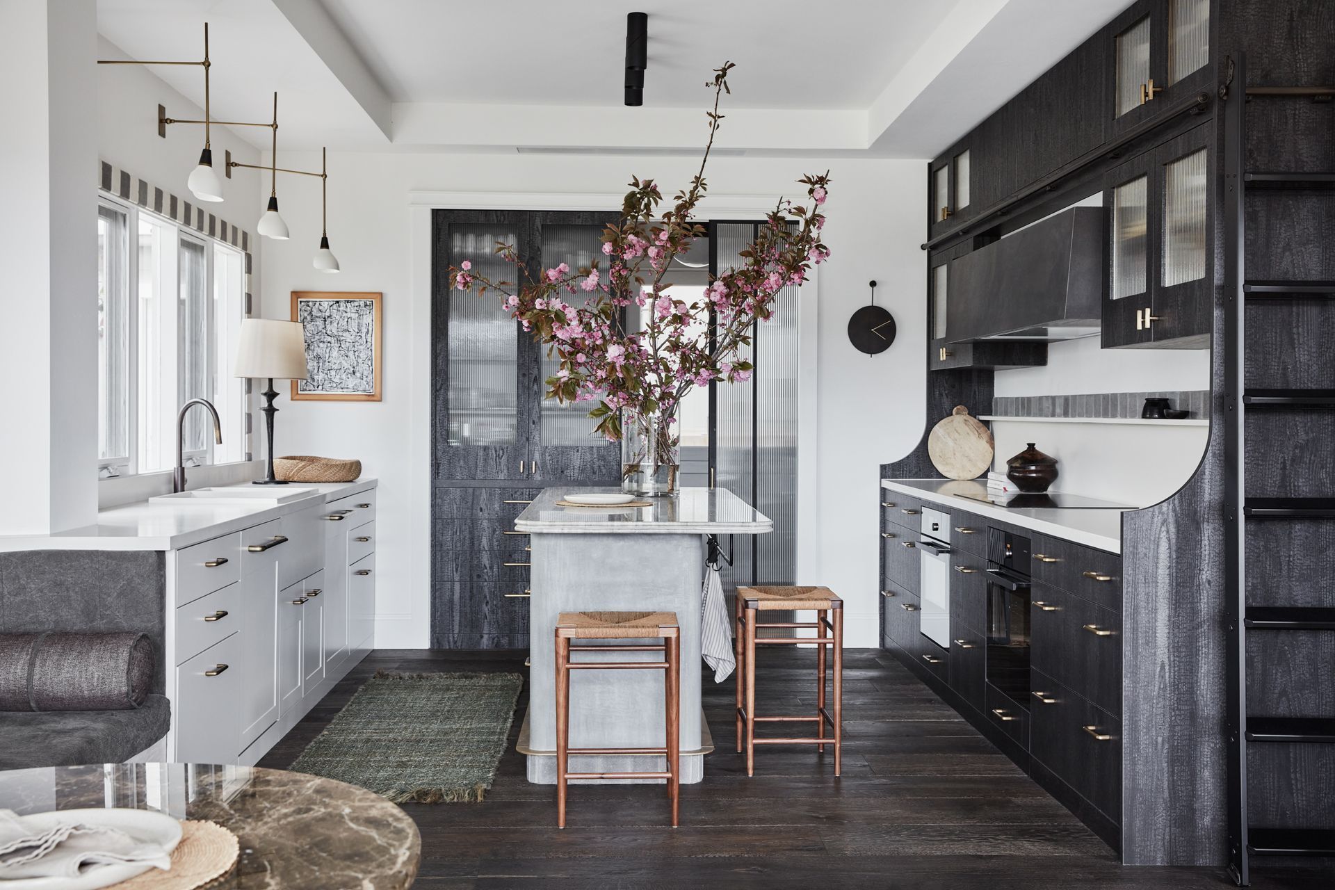 KITCHEN Joinery in Eveneer Shou Sugi Ban veneer, Elton Group, and Dulux White Beach Half. Polished micro-cement island, Idea Creations. Benchtops in Ocean Blue Travertine (island), Artedomus, and Smartstone Blanco Naturale. Brodware ‘City Stik’ pull-out kitchen mixer, Sydney Tap and Bathroomware. Biancone and Tunis Grigio wall tiles, Aeria Country Floors. 75 Caliber ceiling lights, Est Lighting. Torno wall sconces, Blueprint Lighting. V-Zug induction cooktop, electric oven and combi-steam oven, and Miele integrated dishwasher, all Winning Appliances. Armadillo ‘Terra’ jute runner, Kate Nixon. Mel Smilow stools, 1stDibs.