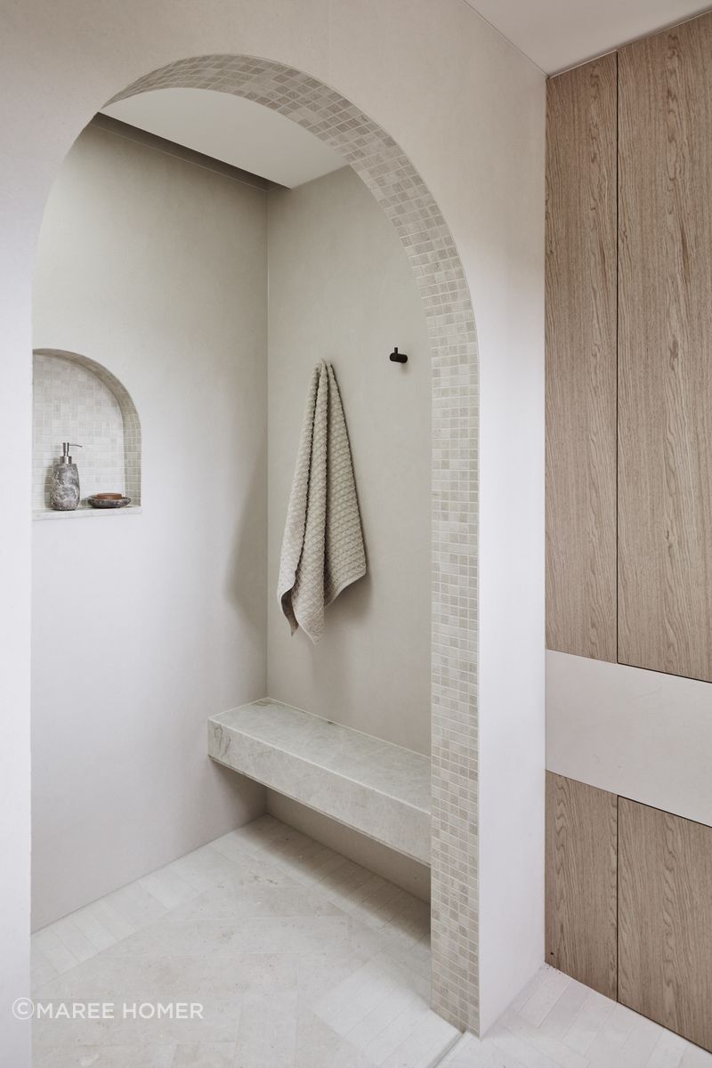 MAIN ENSUITE Kone White matt wall tiles and benchtop, Rocks On. Raw-sawn limestone floor tiles and porcelain matt arch mosaics, all Onsite Supply+Design. Bouchon veneer, Briggs Veneers.