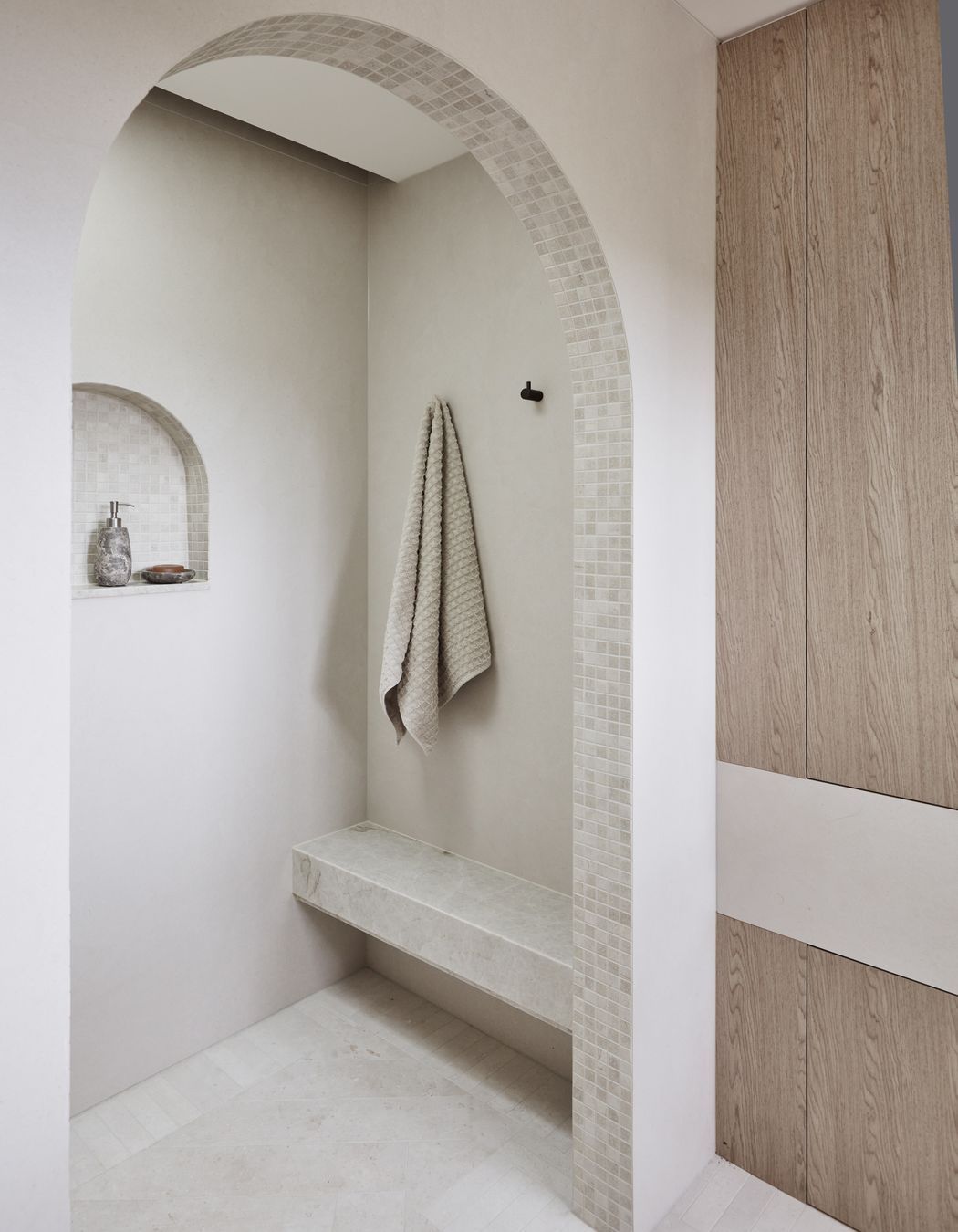 MAIN ENSUITE Kone White matt wall tiles and benchtop, Rocks On. Raw-sawn limestone floor tiles and porcelain matt arch mosaics, all Onsite Supply+Design. Bouchon veneer, Briggs Veneers.