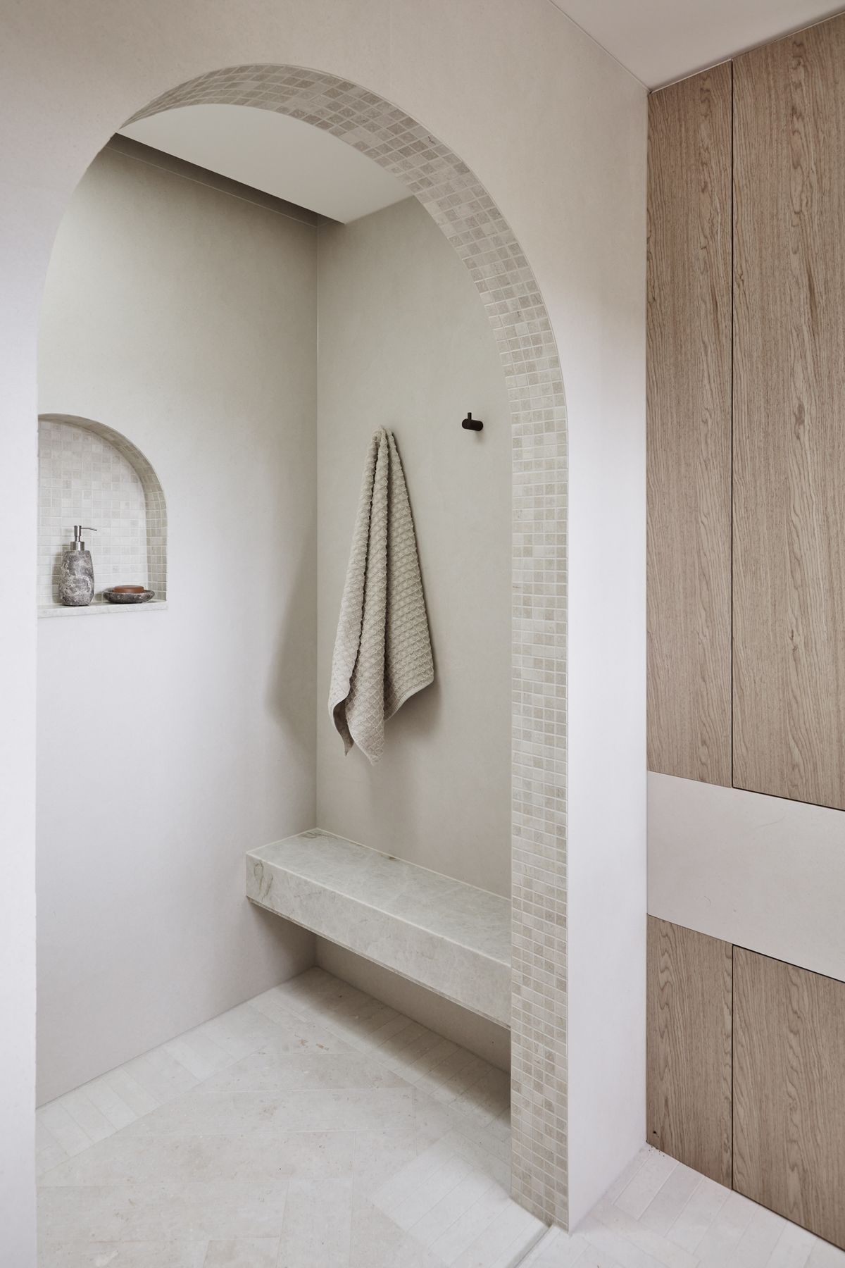 MAIN ENSUITE Kone White matt wall tiles and benchtop, Rocks On. Raw-sawn limestone floor tiles and porcelain matt arch mosaics, all Onsite Supply+Design. Bouchon veneer, Briggs Veneers.