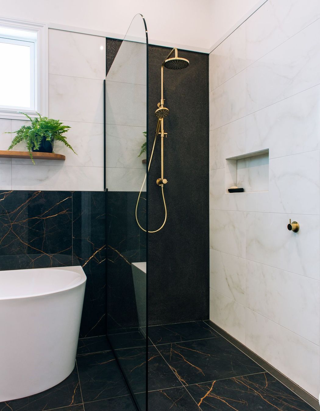 Rounded glazing and integrated channel drain maximise the features of this tiled shower.