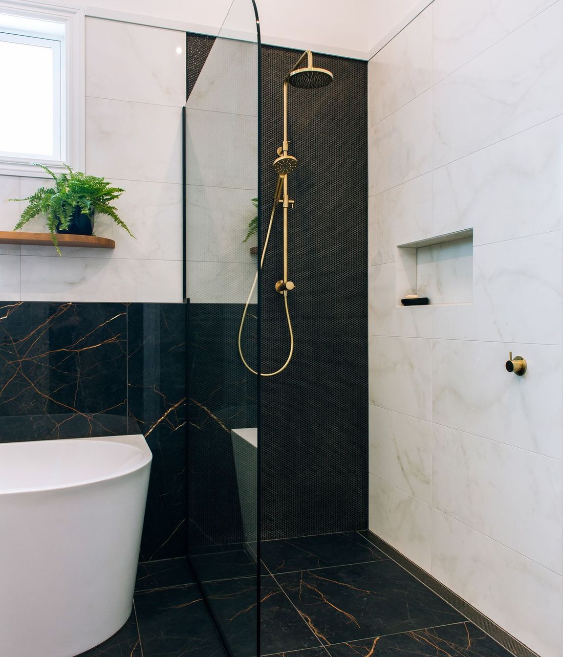 Rounded glazing and integrated channel drain maximise the features of this tiled shower.
