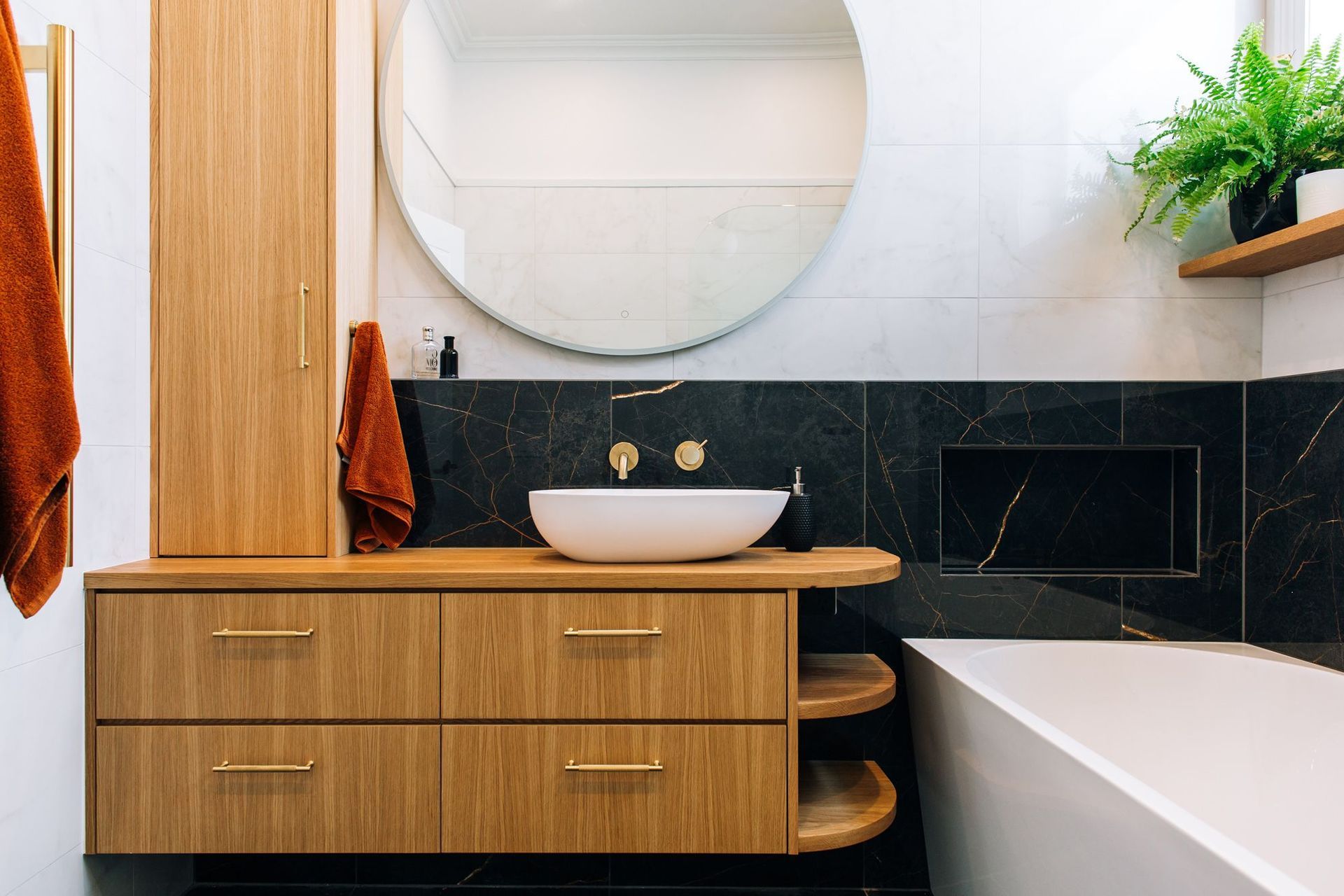 Custom joinery with an off-centre vessel basin, and brass hardware.