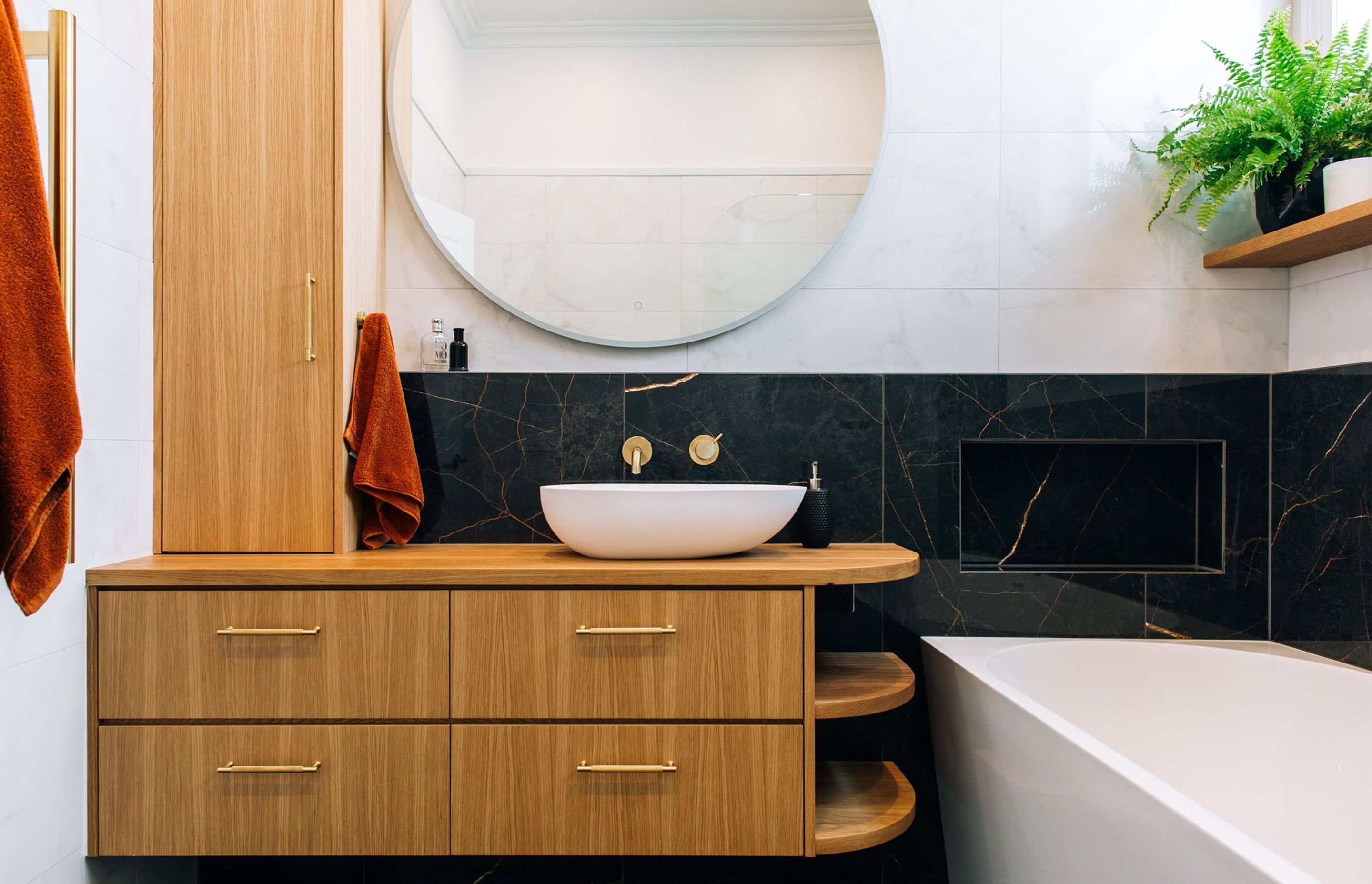 Custom joinery with an off-centre vessel basin, and brass hardware.