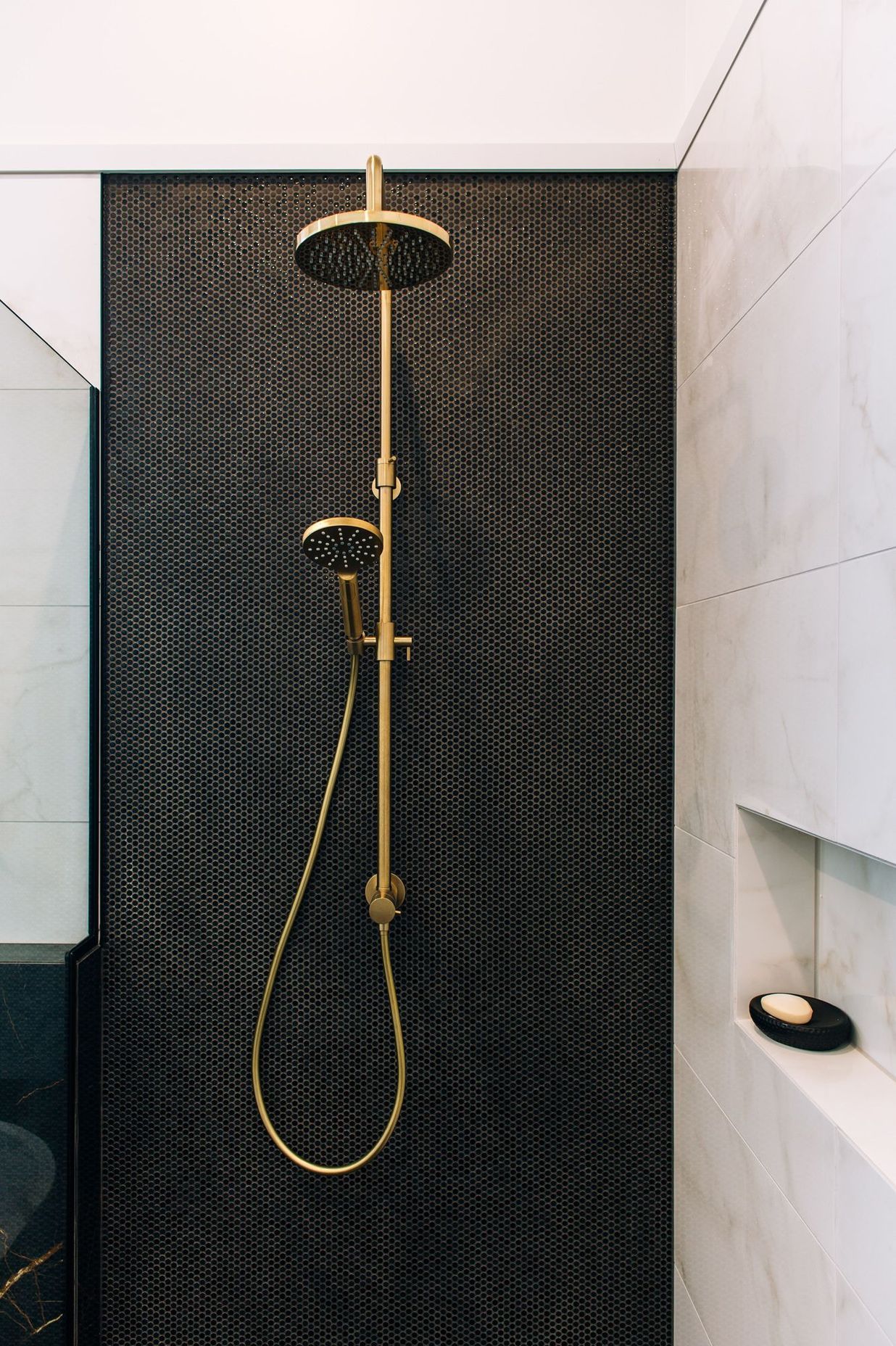 Dual shower heads on the mosaic tiled wall.