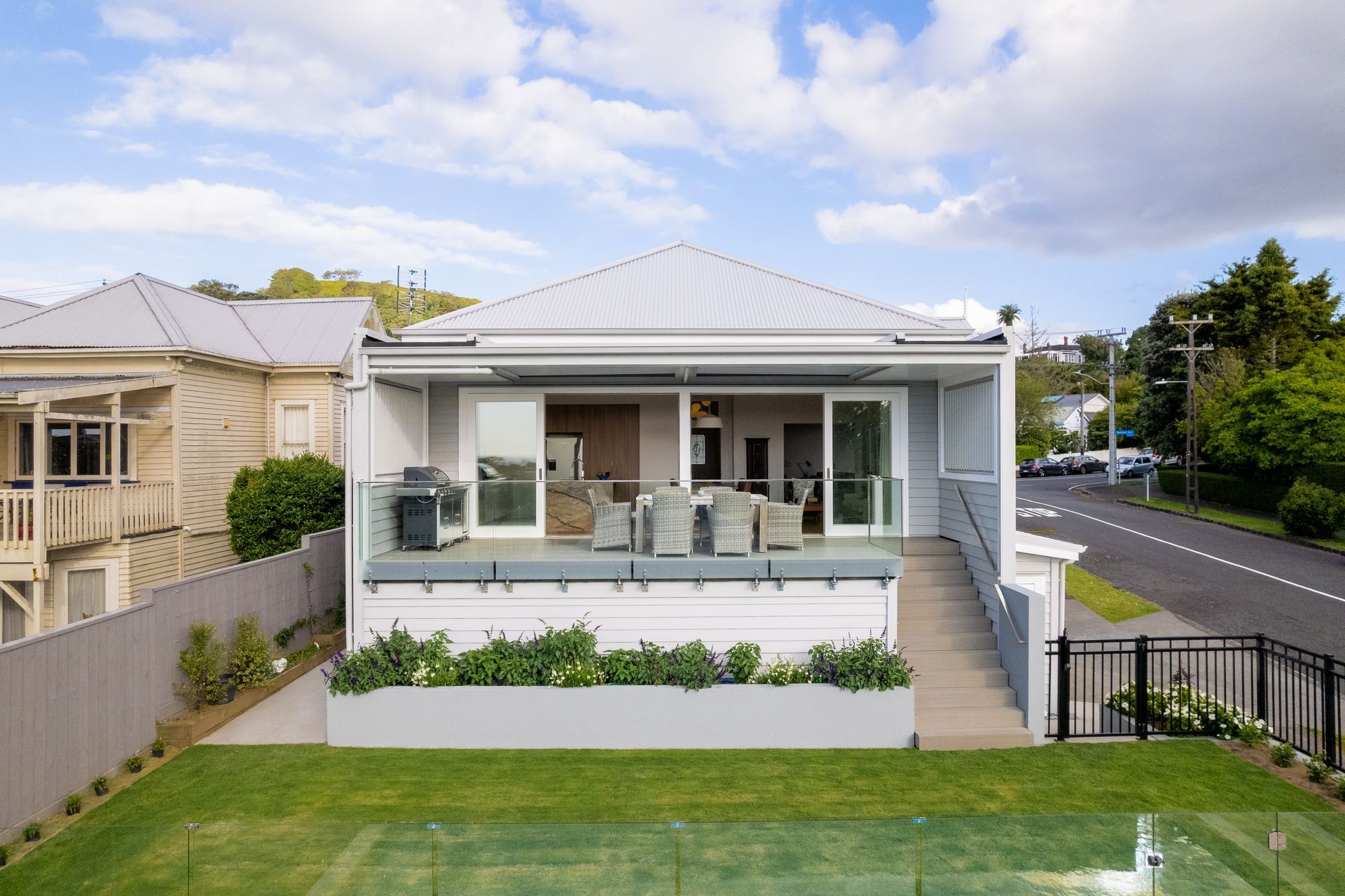 Looking back at the house from the pool, louvres at each side of the deck provide privacy from the neighbours and the street, while the planter box soften the transition to the level lawn.