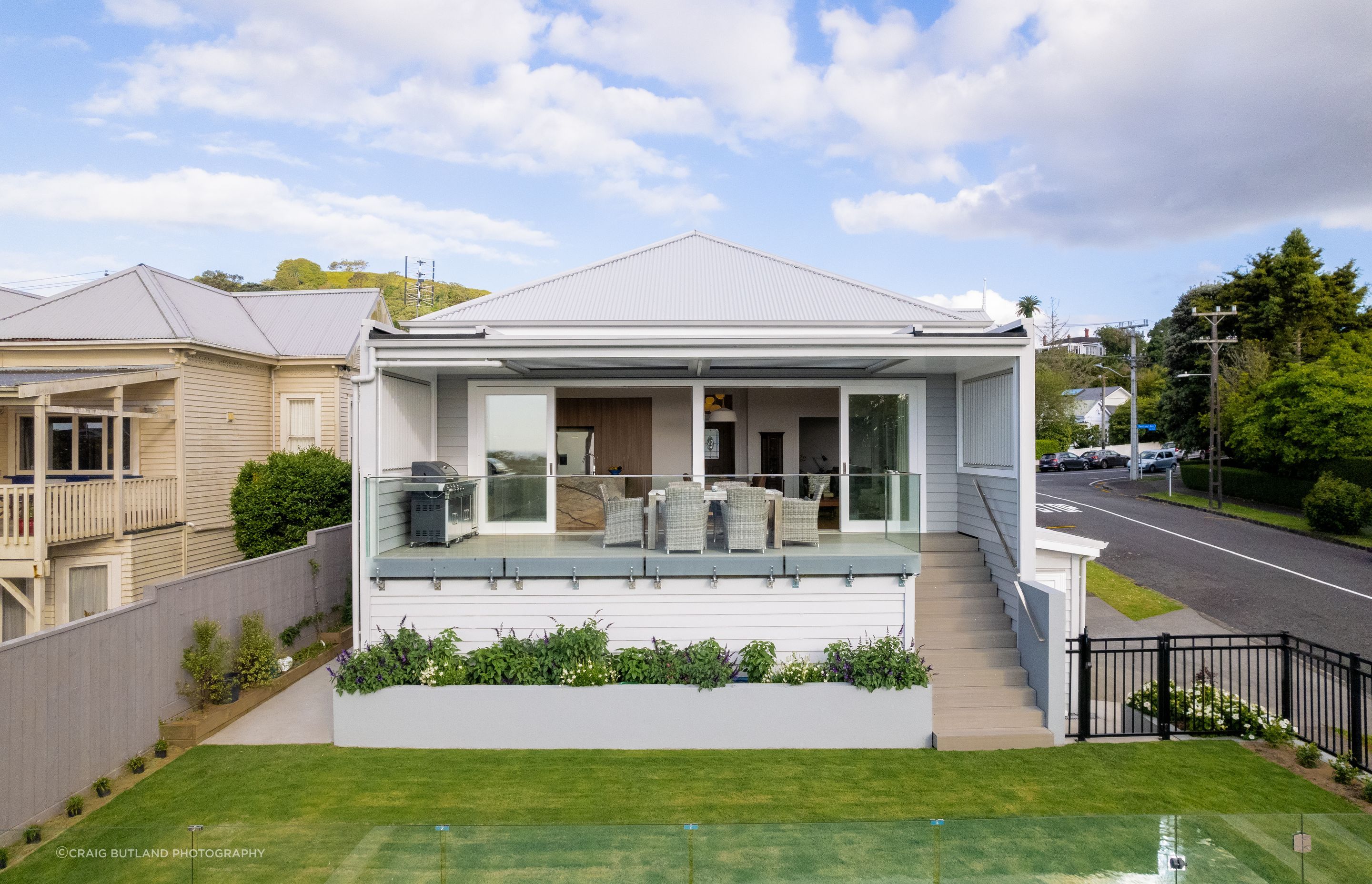 Looking back at the house from the pool, louvres at each side of the deck provide privacy from the neighbours and the street, while the planter box soften the transition to the level lawn.