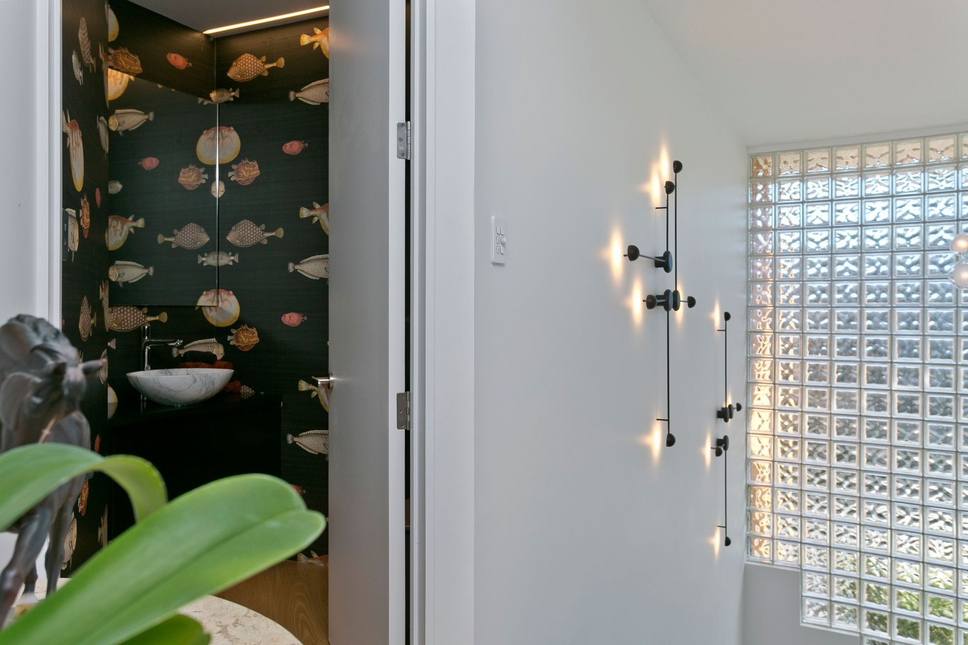 A statement wallpaper in the powder room contrasts the mainly neutral tones of the interior palette, adding a touch of drama to the scheme.