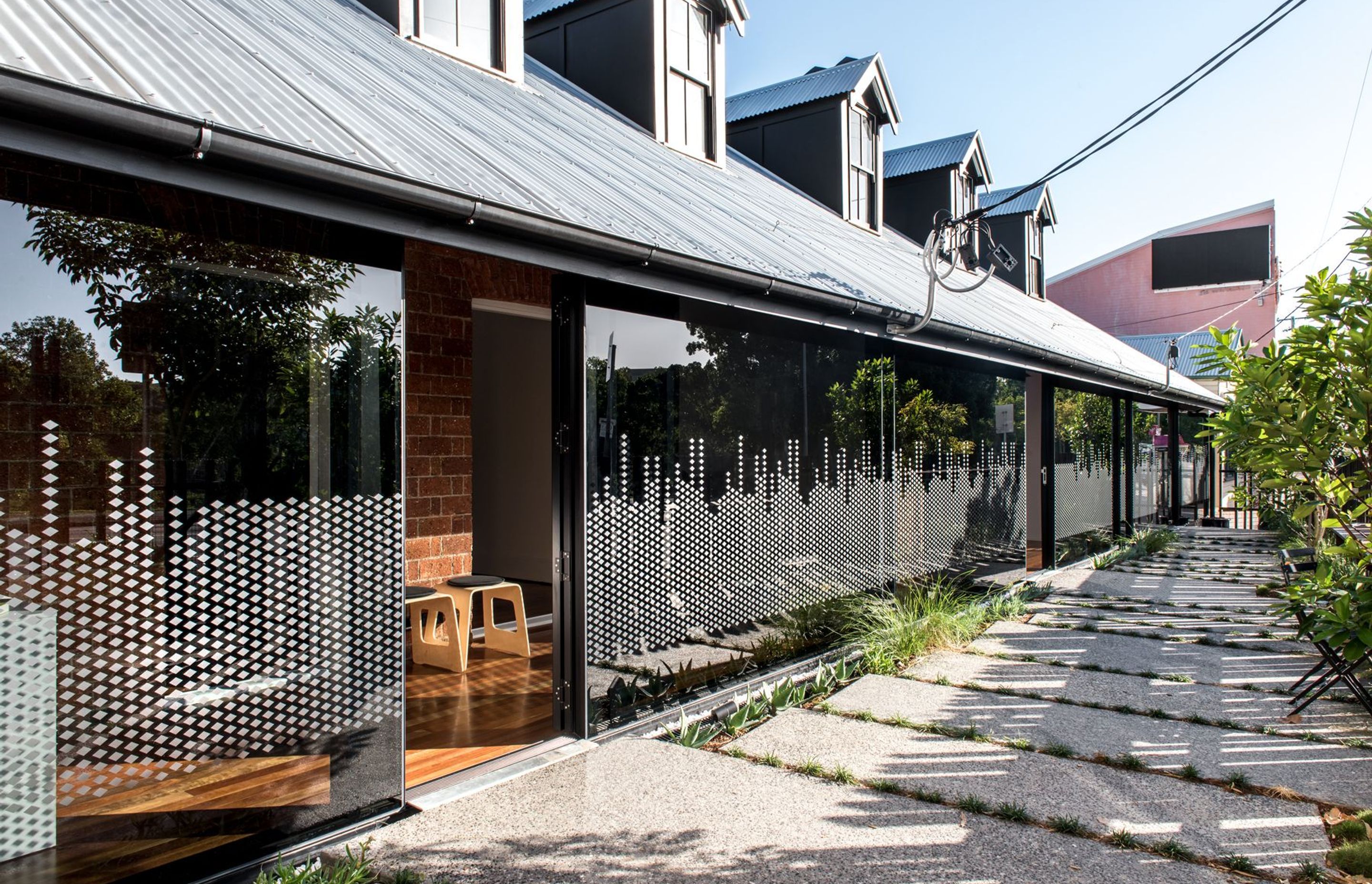 Photography: Cathy Schusler | The glass facade mutates from a visual protection during the day to nearly dissolving during the night, where full emphasis is given to the brick facade behind.