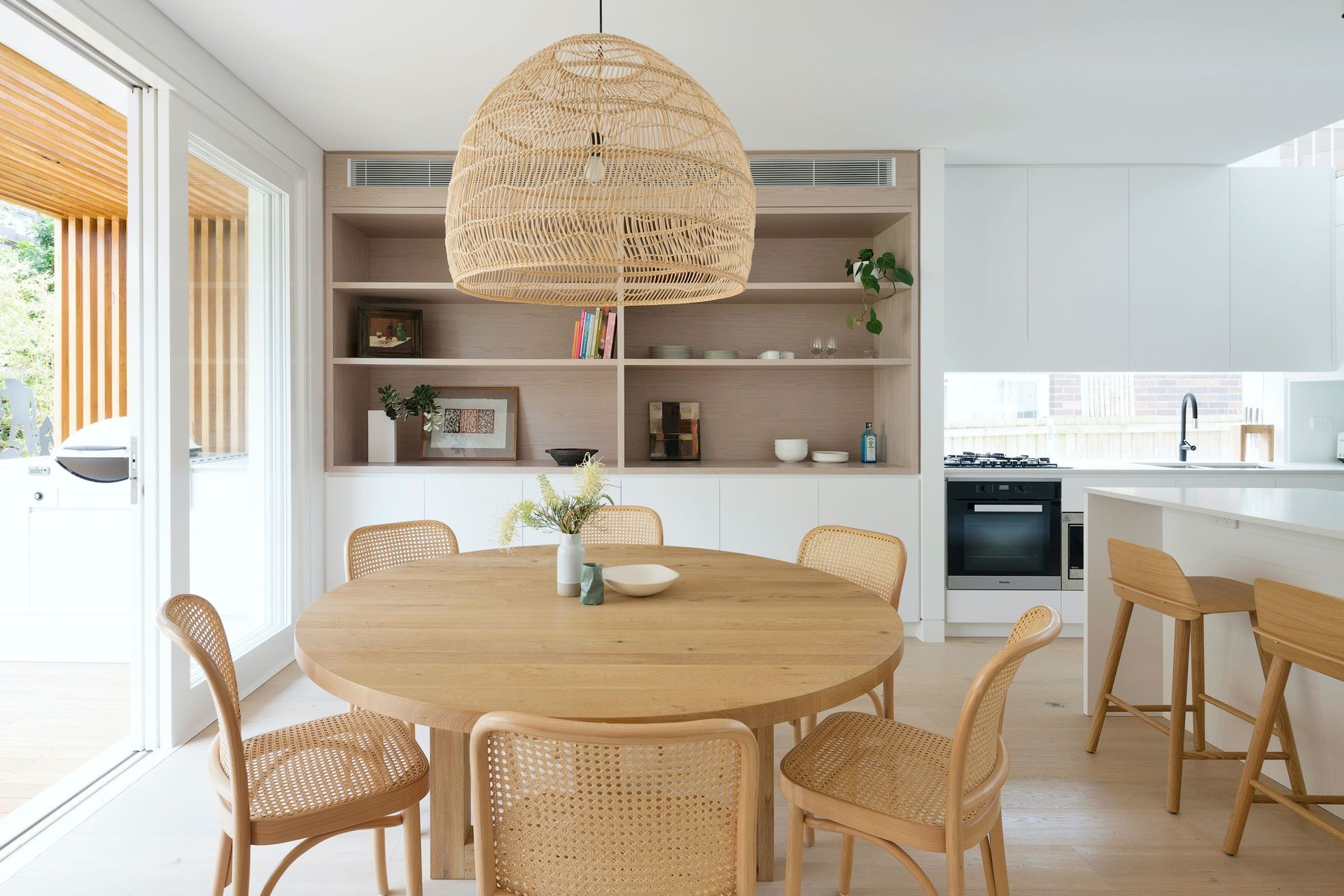 A fluid dining and kitchen space lined in natural finishes .