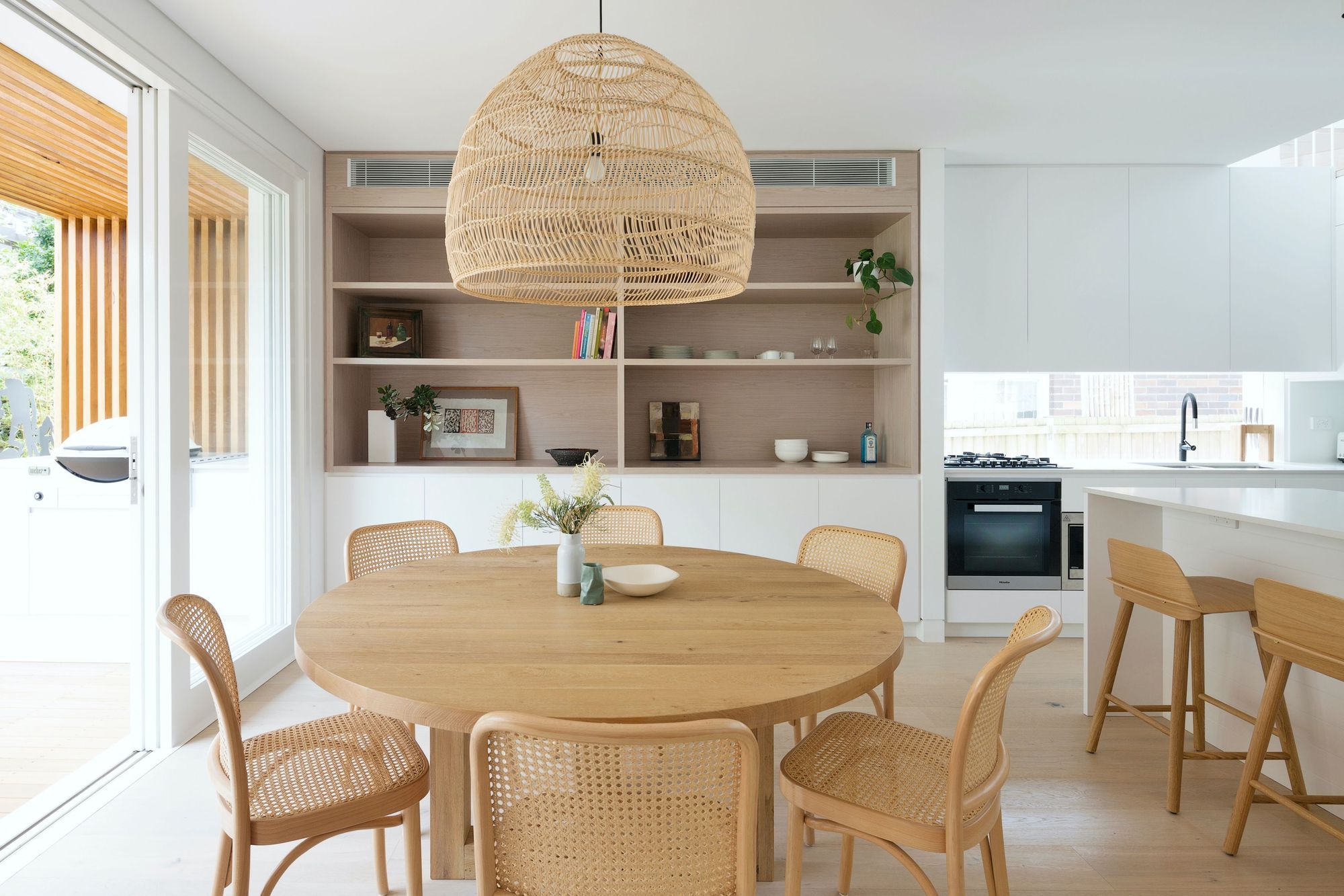 A fluid dining and kitchen space lined in natural finishes .