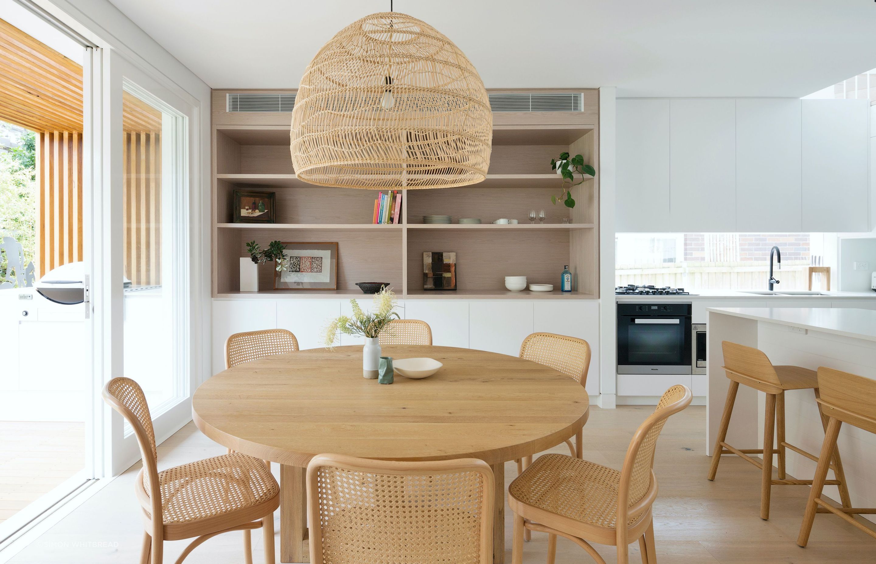 A fluid dining and kitchen space lined in natural finishes .