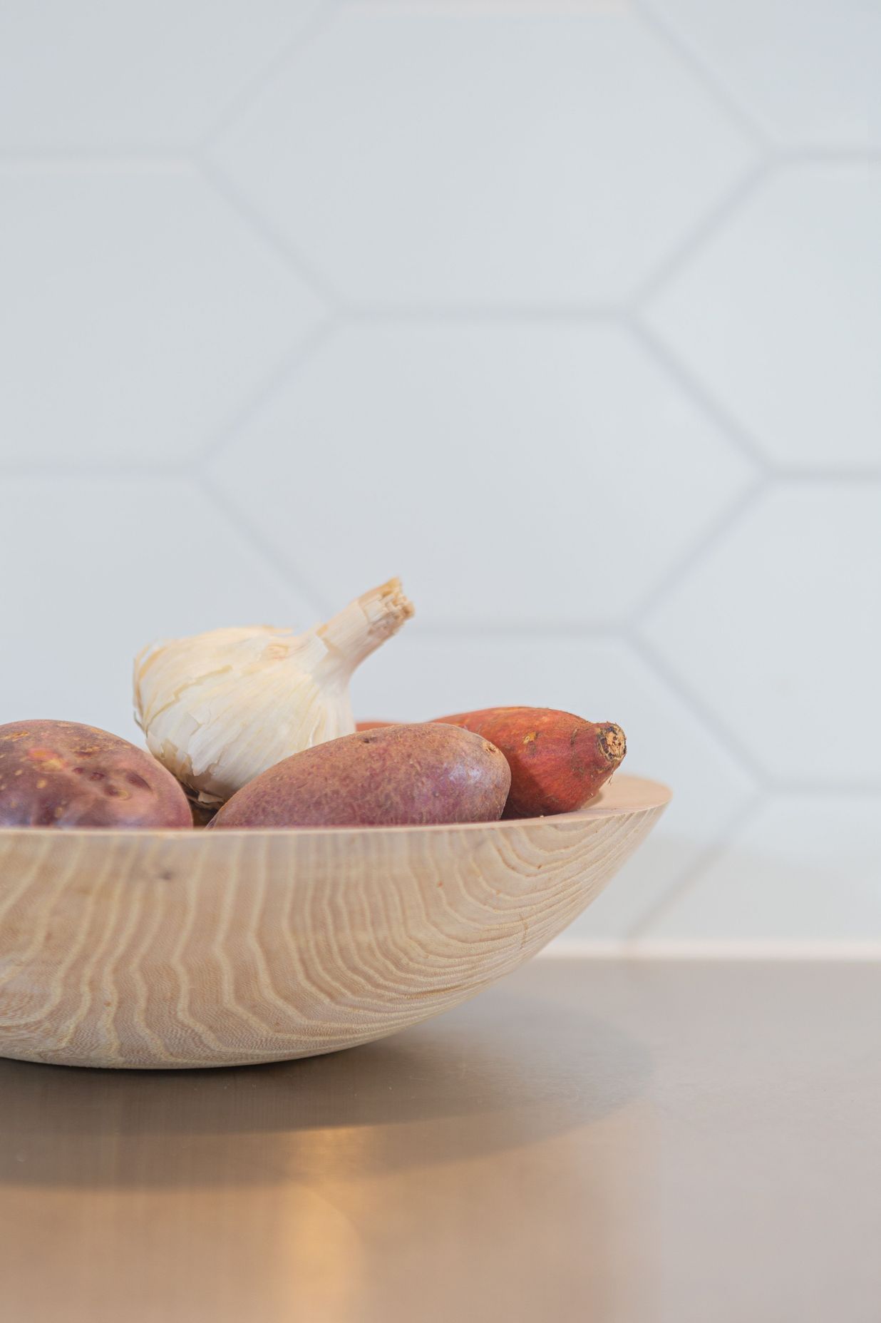 Elongated hexagonal tiles and a stainless steel benchtop add to the textures and practicality of this kitchen.