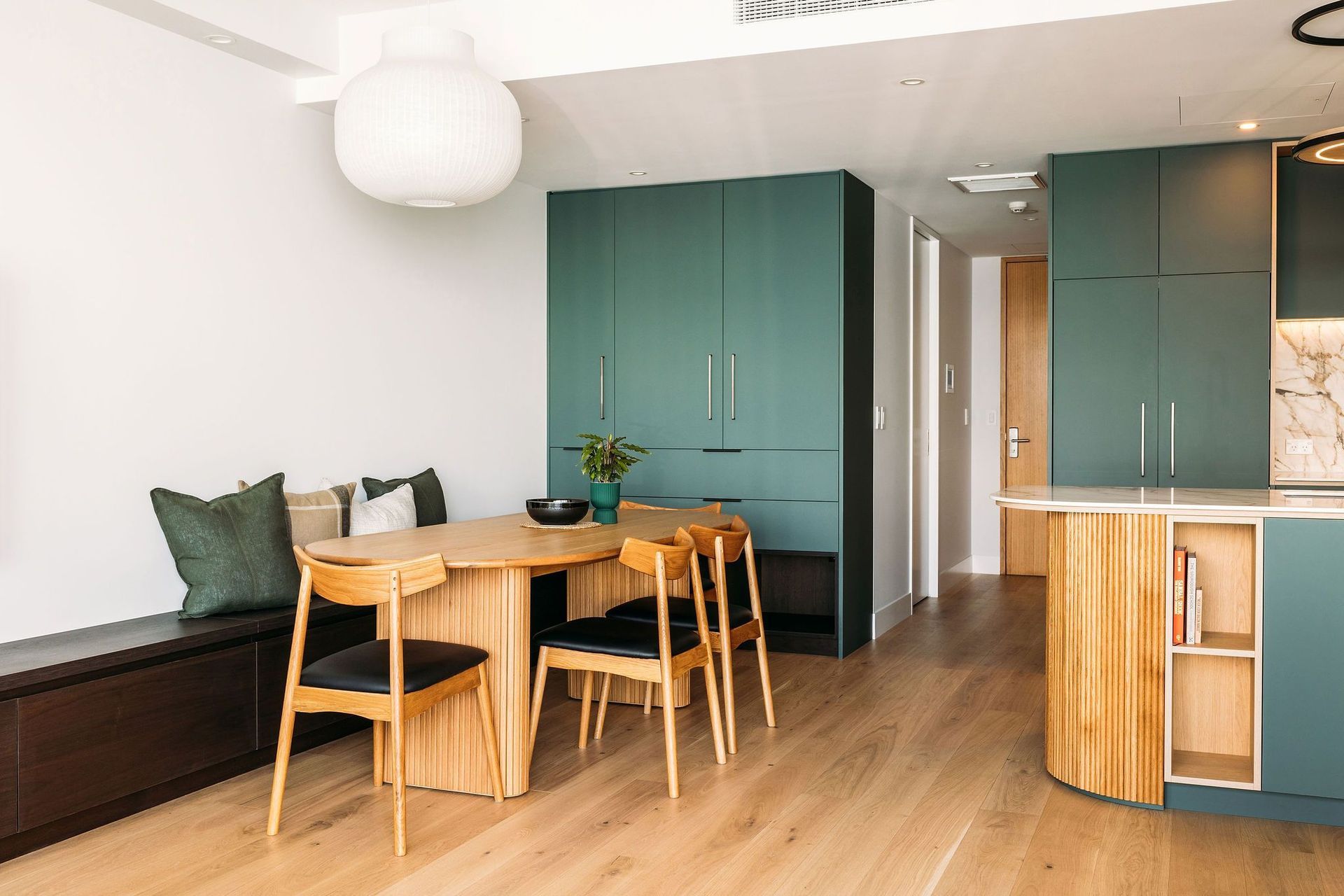 Custom cabinetry - a walnut veneer bench seat extends from the dining table - the full length of the room.
