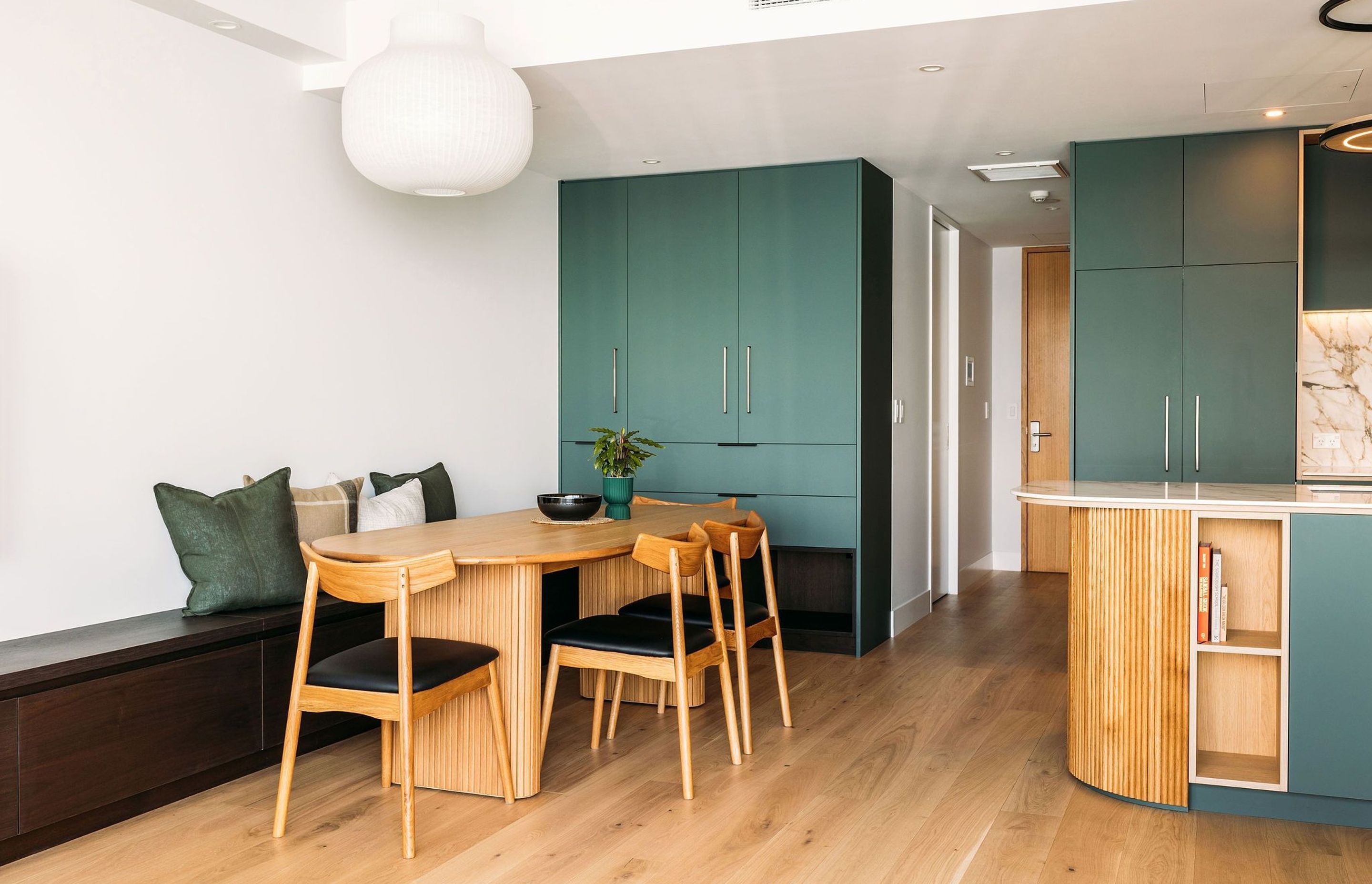 Custom cabinetry - a walnut veneer bench seat extends from the dining table - the full length of the room.