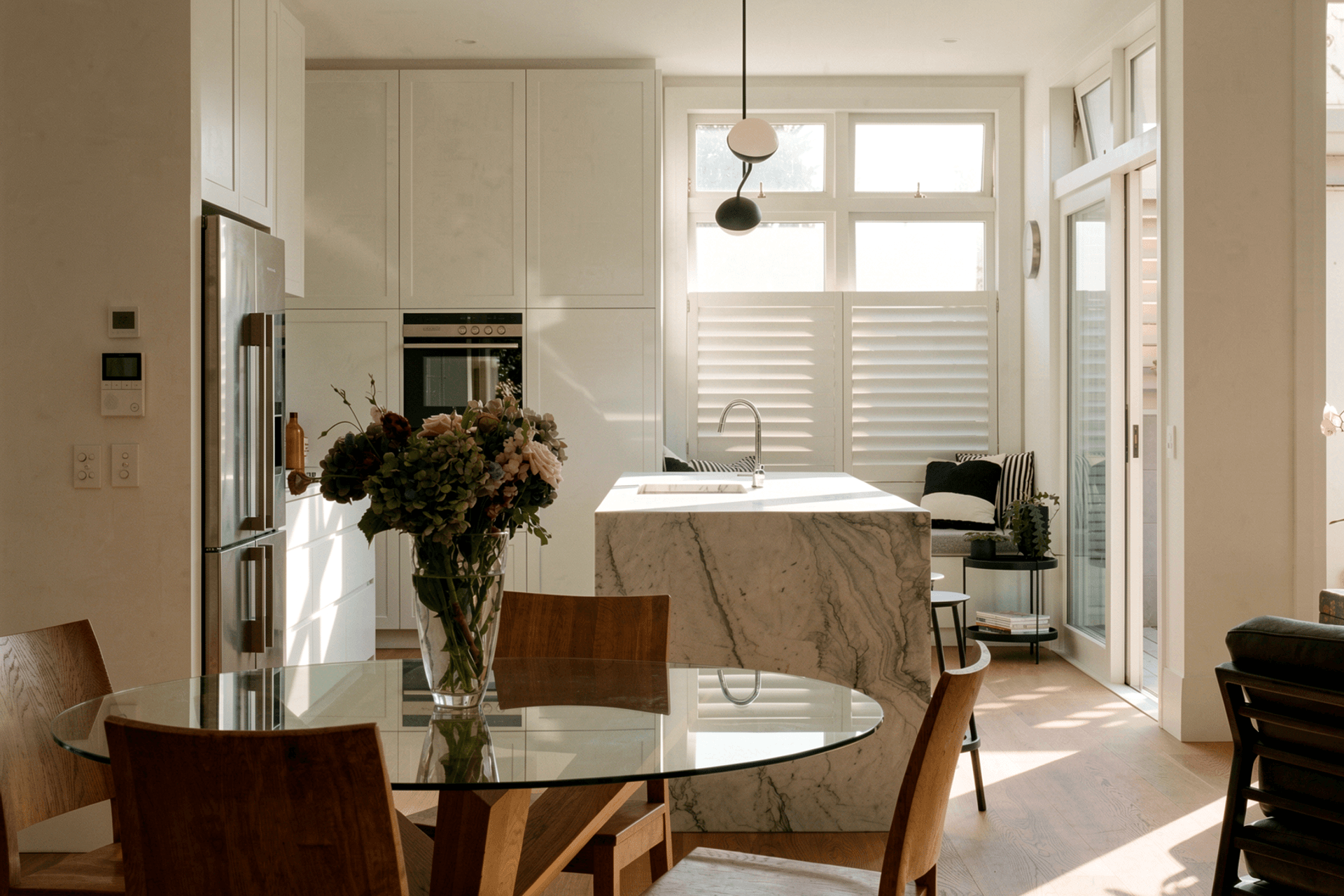Viewed from the dining room, the kitchen is designed as a calm and enduring centre for family life. Soft grey cabinetry is paired with natural materials and carefully considered detailing, creating a timeless space that feels both sophisticated and welcoming. Its open relationship with the dining area encourages connection, making it equally suited to everyday routines and relaxed entertaining.