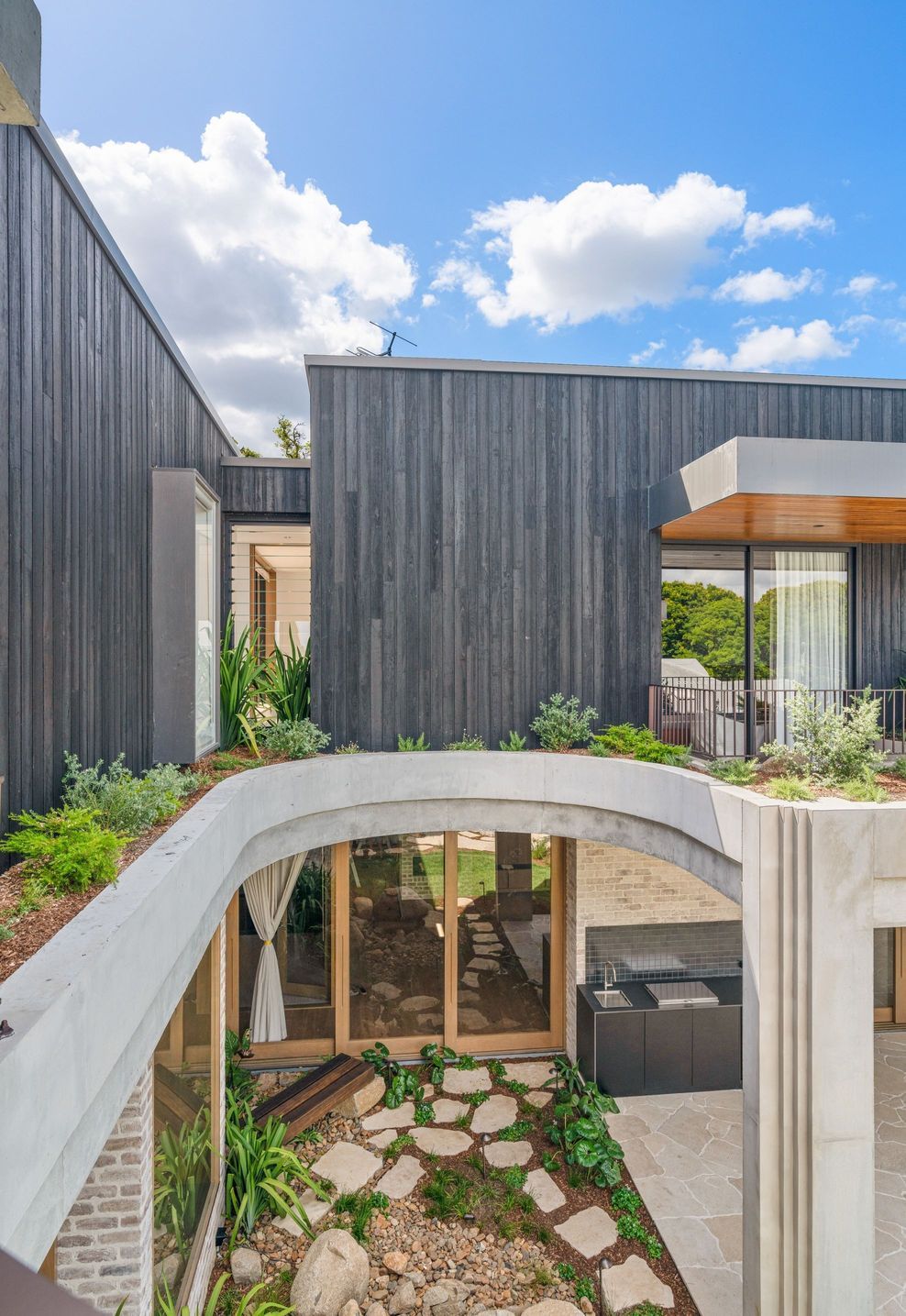 Curved structural concrete frames the internal courtyard — quiet engineering in service of garden and light.