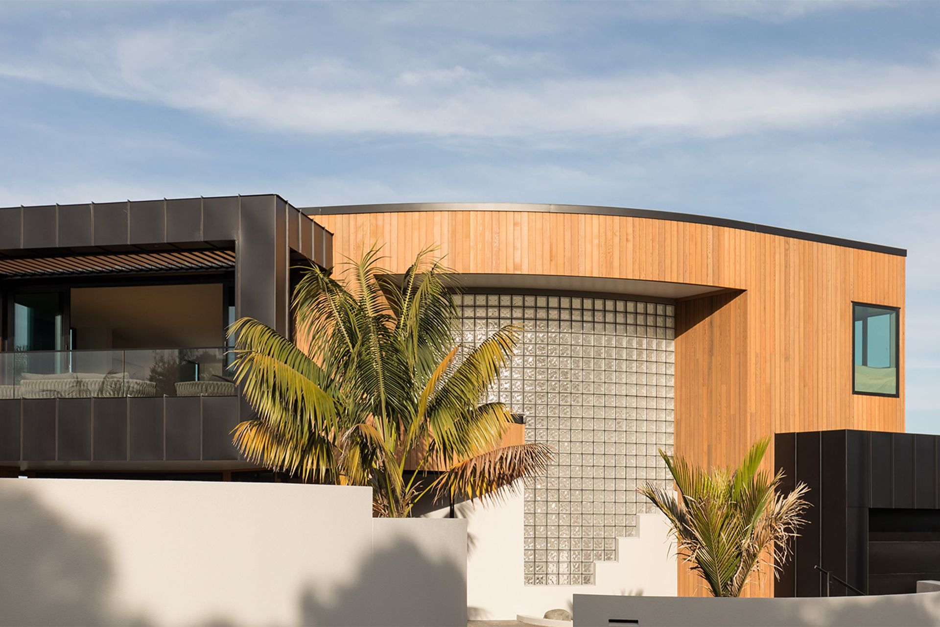 The plaster exterior has been replaced with a combination of vertical cedar and standing seam cladding for a crisp, contemporary look—only the glass bricks give a nod to the home's origins.