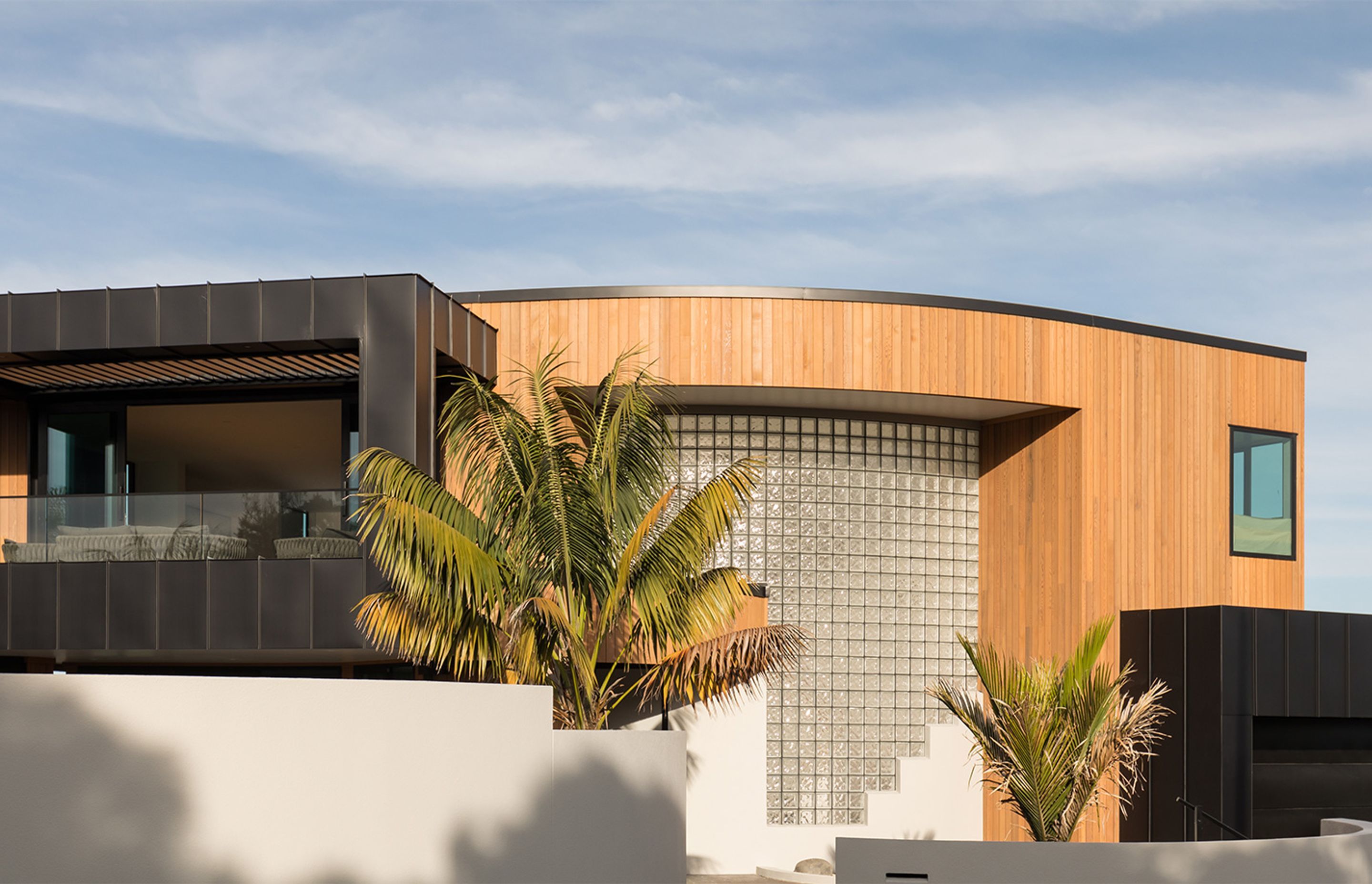 The plaster exterior has been replaced with a combination of vertical cedar and standing seam cladding for a crisp, contemporary look—only the glass bricks give a nod to the home's origins.