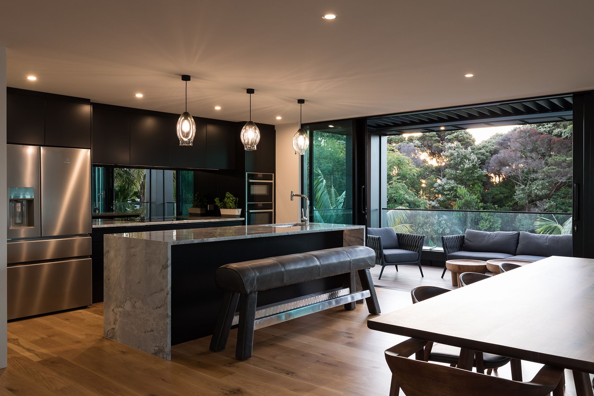 A cantilevered element was added to the front of the home to provide for a much larger outdoor area, which helps take advantage of the leafy outlook and brings a sense of nature indoors—enhanced by the stone benchtops and mirrored splashback.