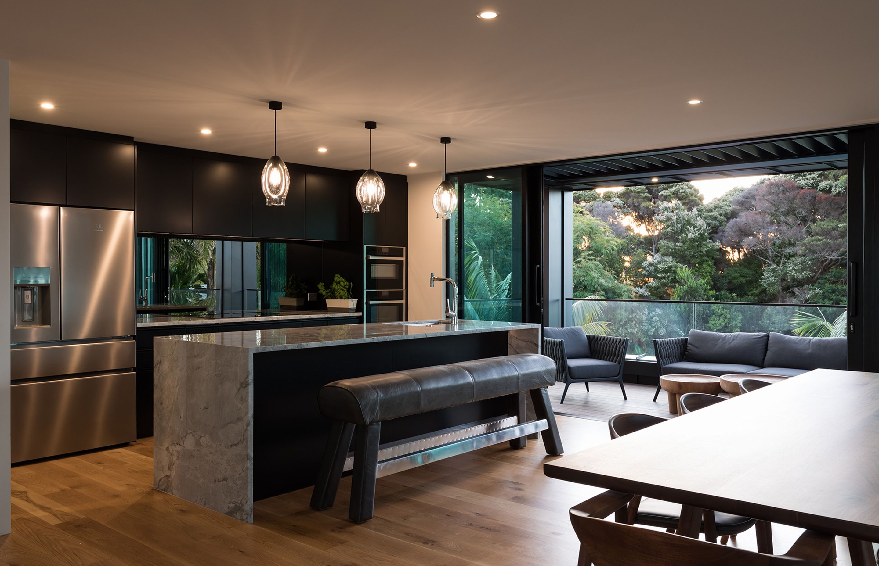 A cantilevered element was added to the front of the home to provide for a much larger outdoor area, which helps take advantage of the leafy outlook and brings a sense of nature indoors—enhanced by the stone benchtops and mirrored splashback.