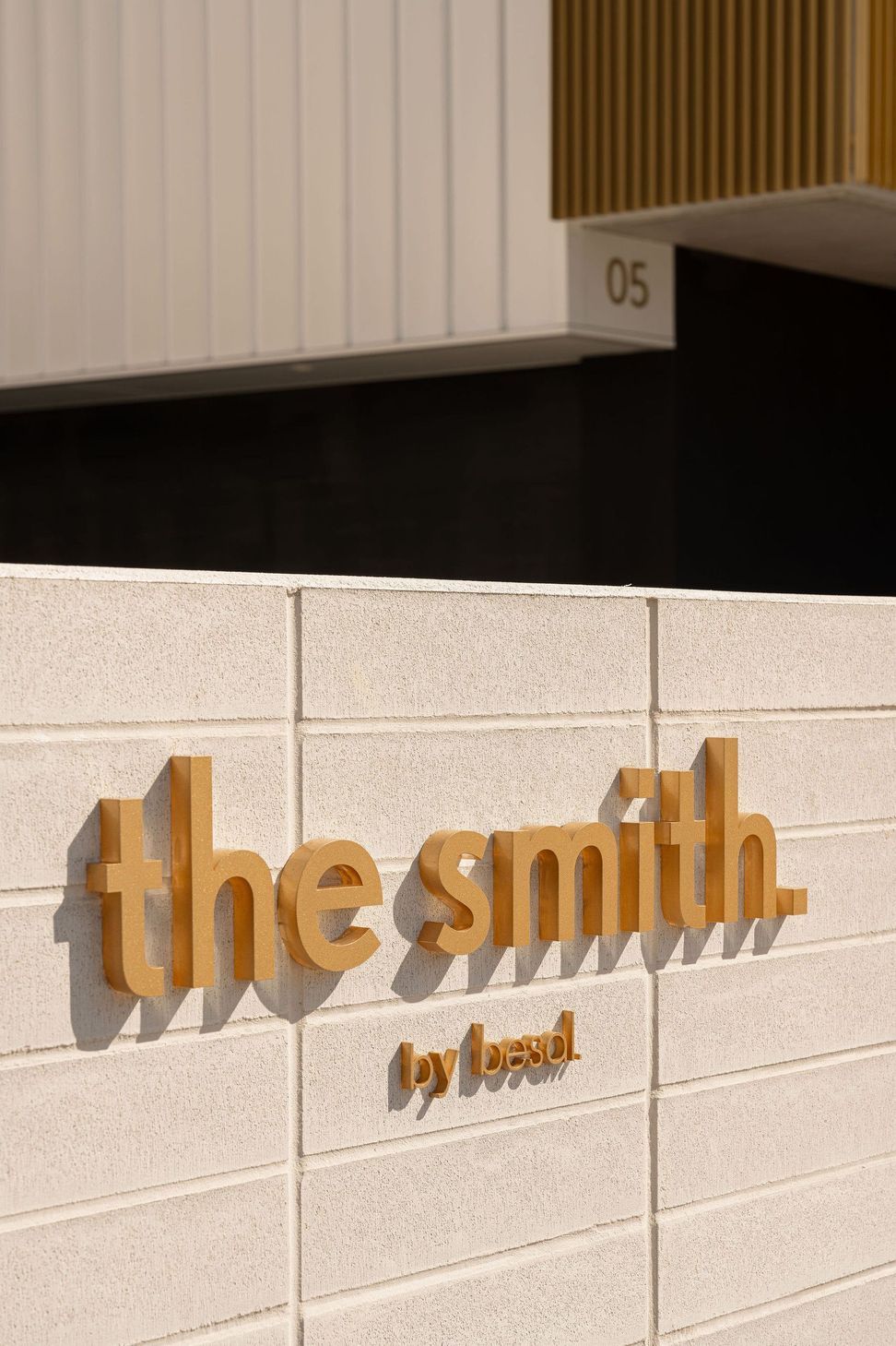 The Smith - Entry. Sculpted signage set into the rendered entry wall.