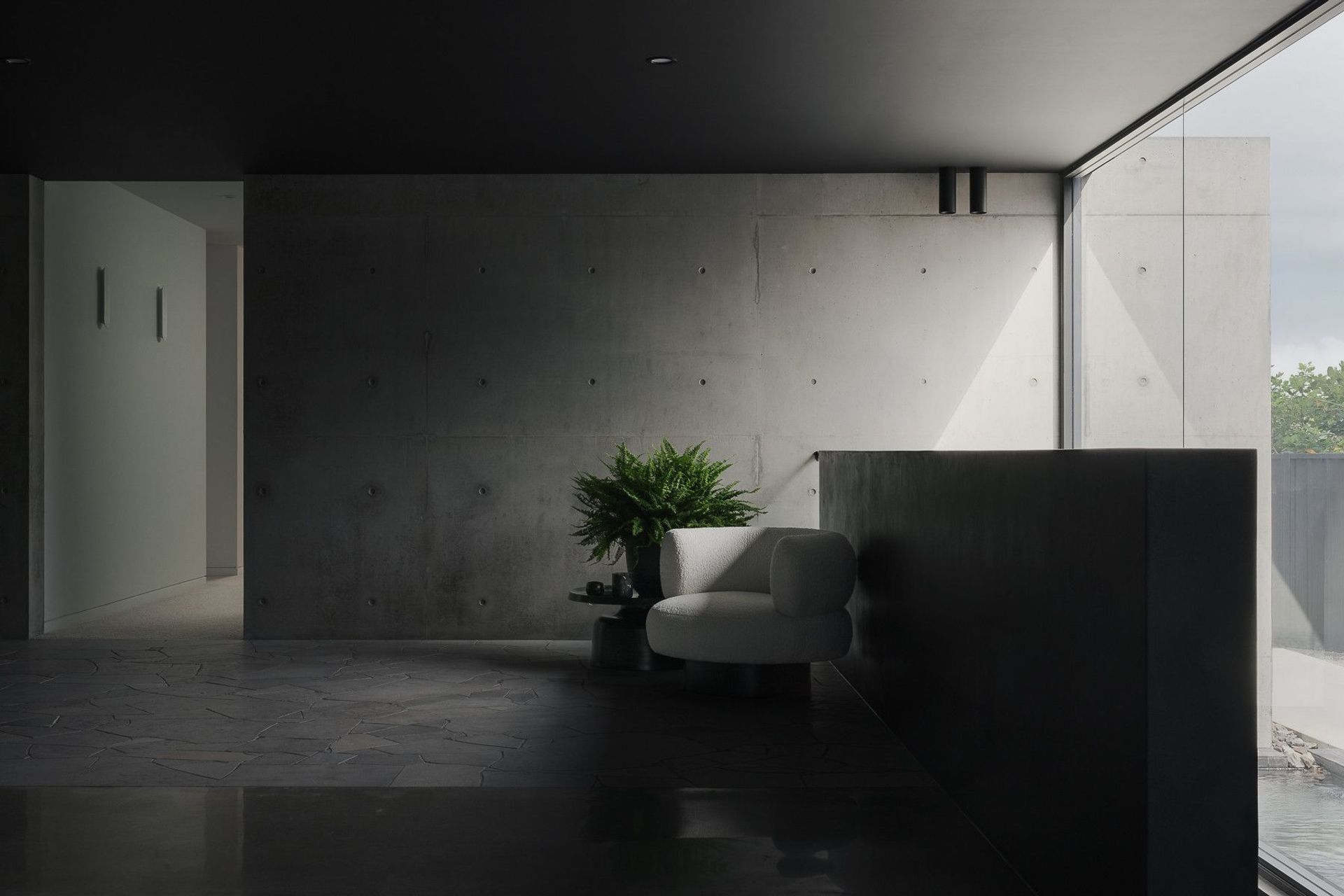 0042 Residence - Living Room. Concrete wall and lounge chair in a quiet corner beside the glazing.