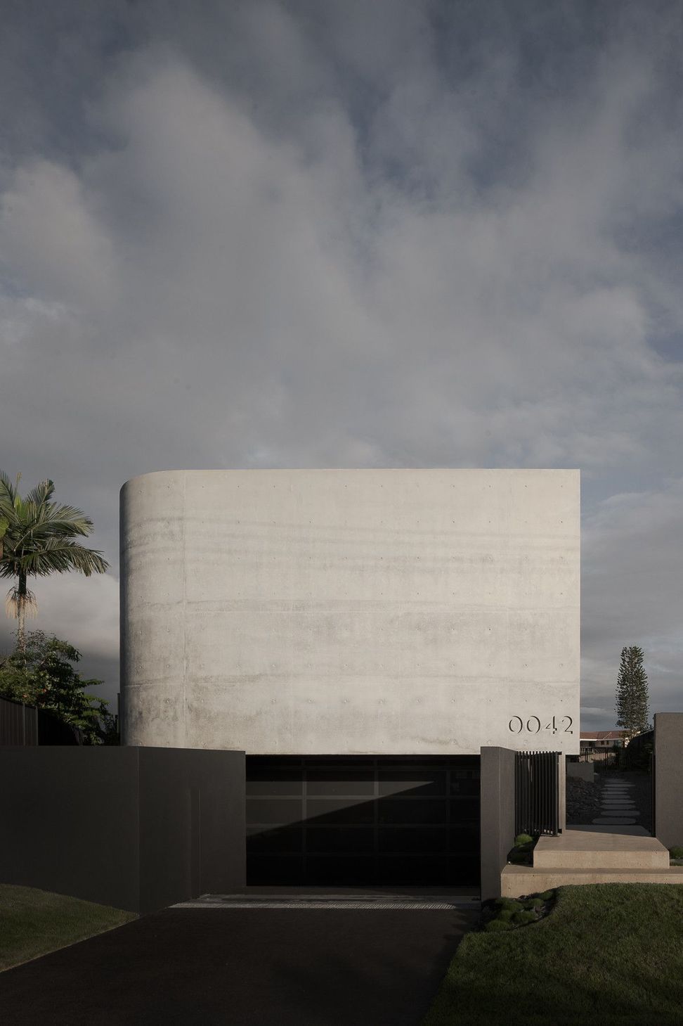 0042 Residence - Exterior. Off-form concrete street wall with the house number set into its surface.