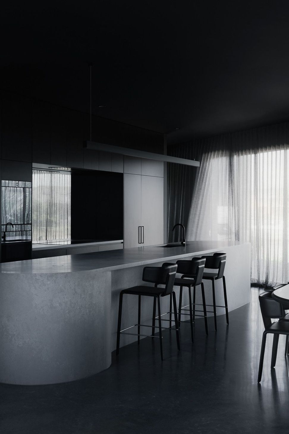 0042 Residence - Kitchen. Curved concrete island with black stools and sheer curtains beyond.