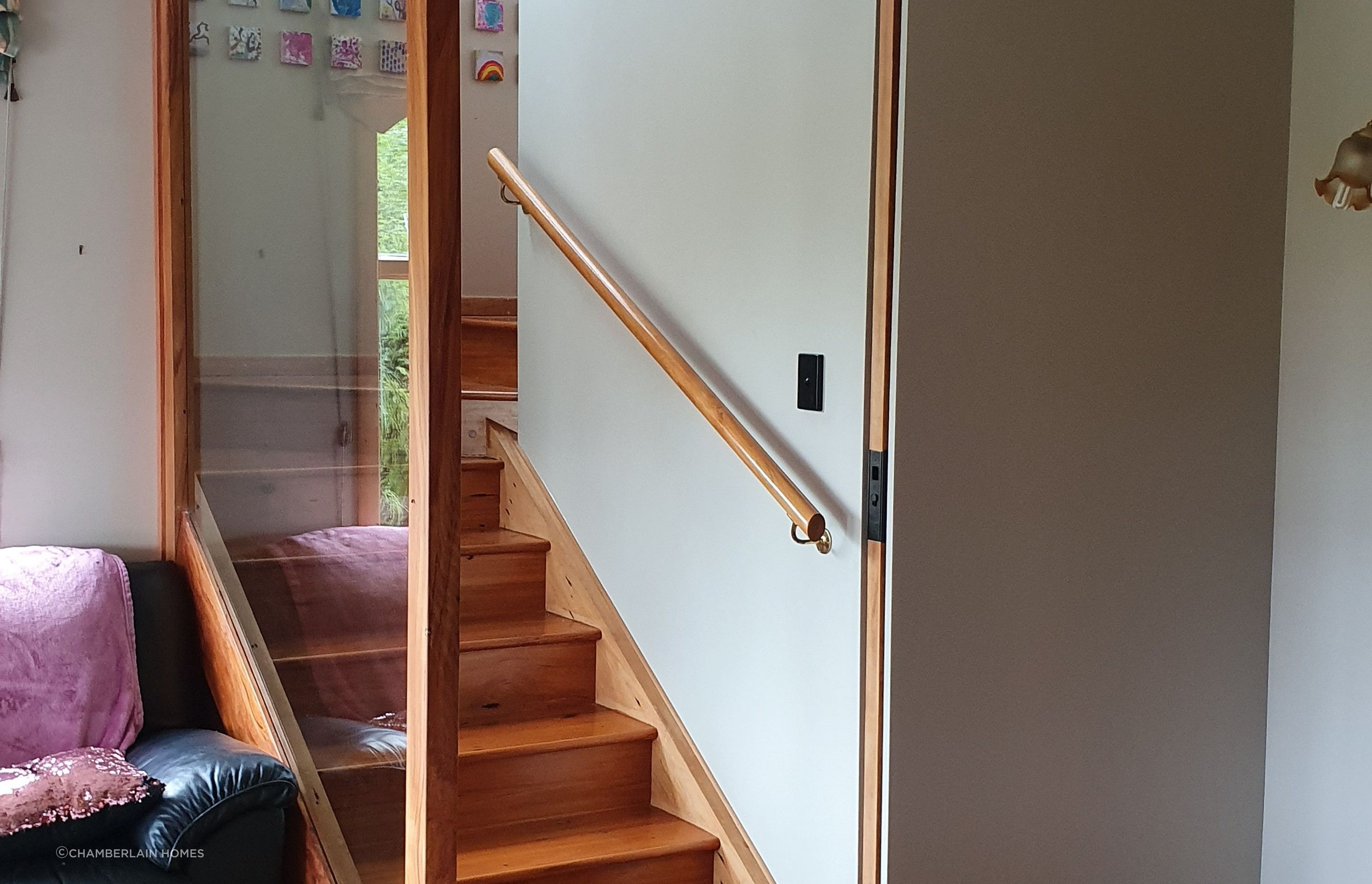 Recycled timber (inset) sliding door and glass panel installed to separate lower section of house from the main part of the house. Glass panel ensures light can circulate and keeps the area looking open.