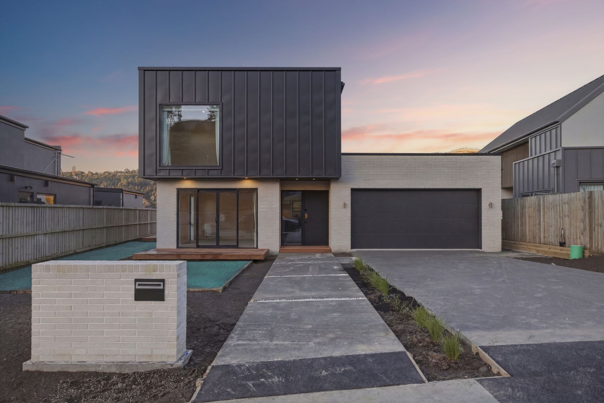 Cashmere Estate new build at dusk, dark cladding and brick exterior, built by Hallmark Homes