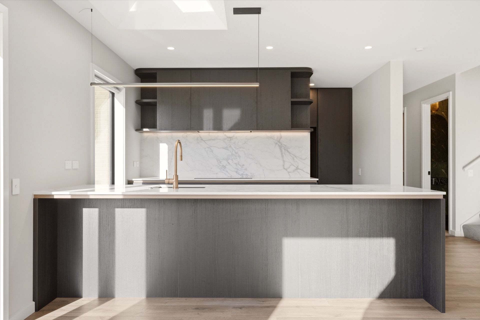 Open plan kitchen with Fiordland Elm Timberland cabinetry and Silestone splashback