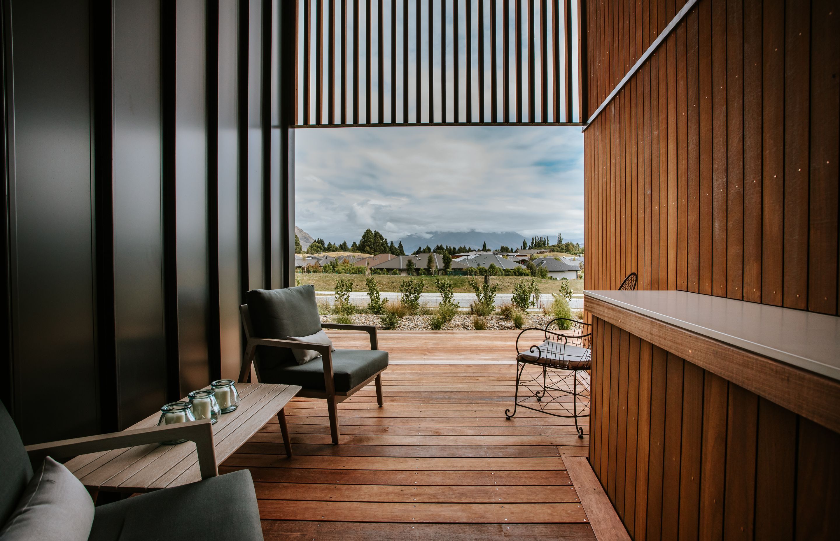 An external sheltered deck space features a built-in bar top in the same material as the kitchen benchtop, creating continuity inside and out.