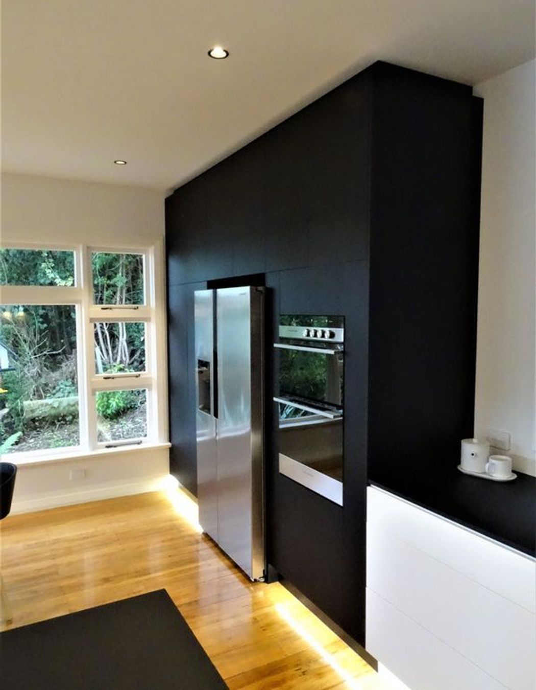 Black kitchen cabinetry ties into the bench top