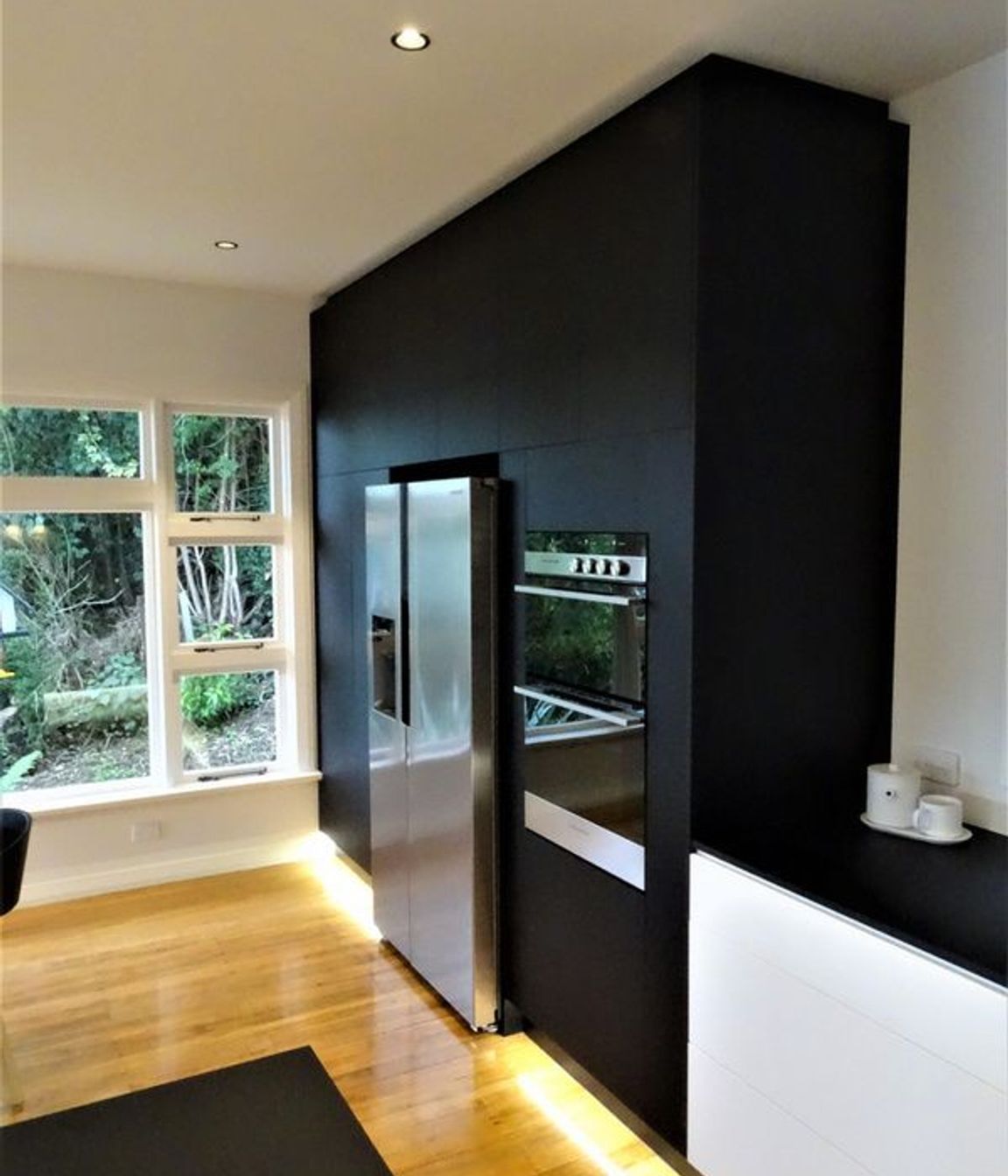Black kitchen cabinetry ties into the bench top