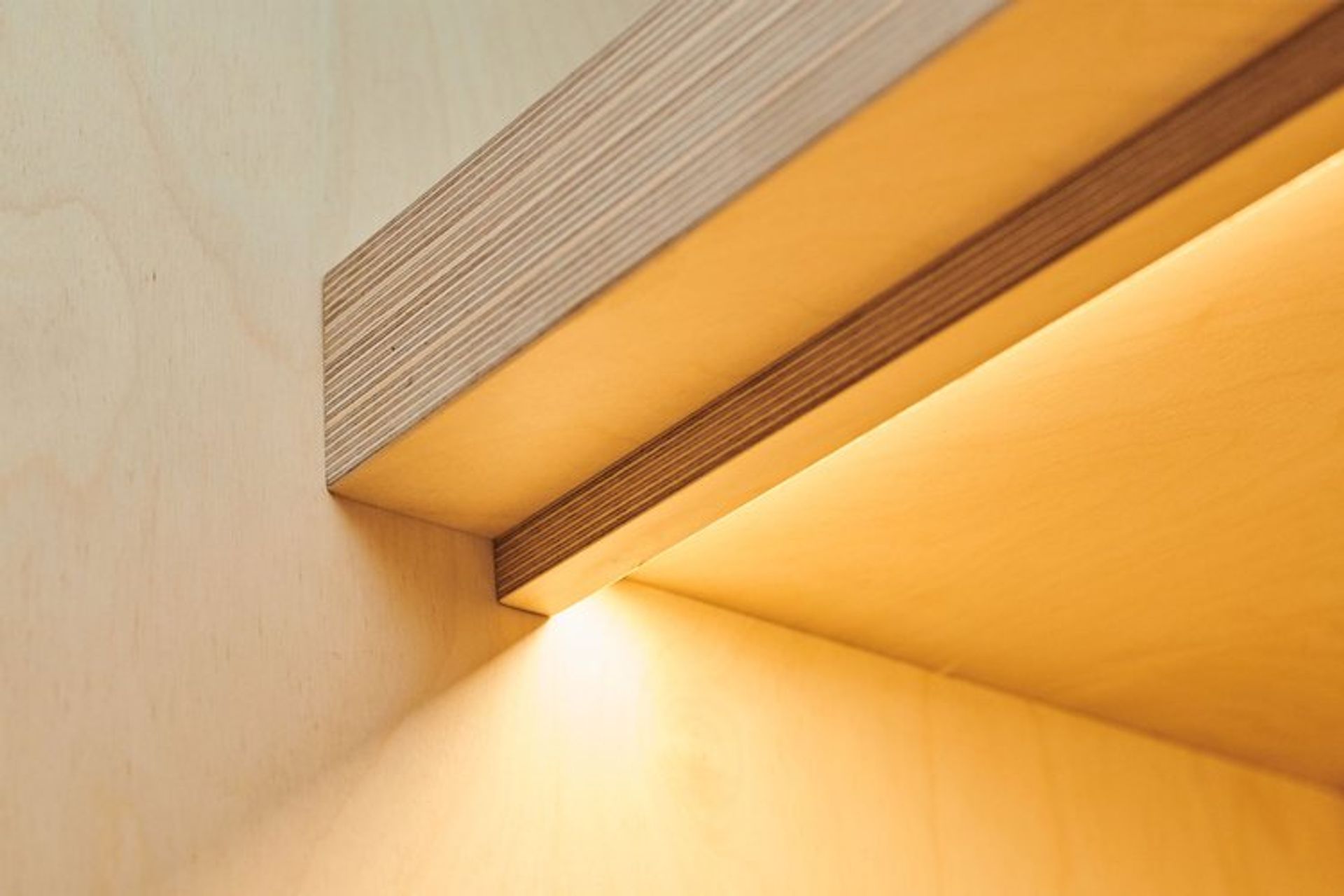 Laminated plywood shelving is lined with LED strip lighting to illuminate the bench top area beneath.