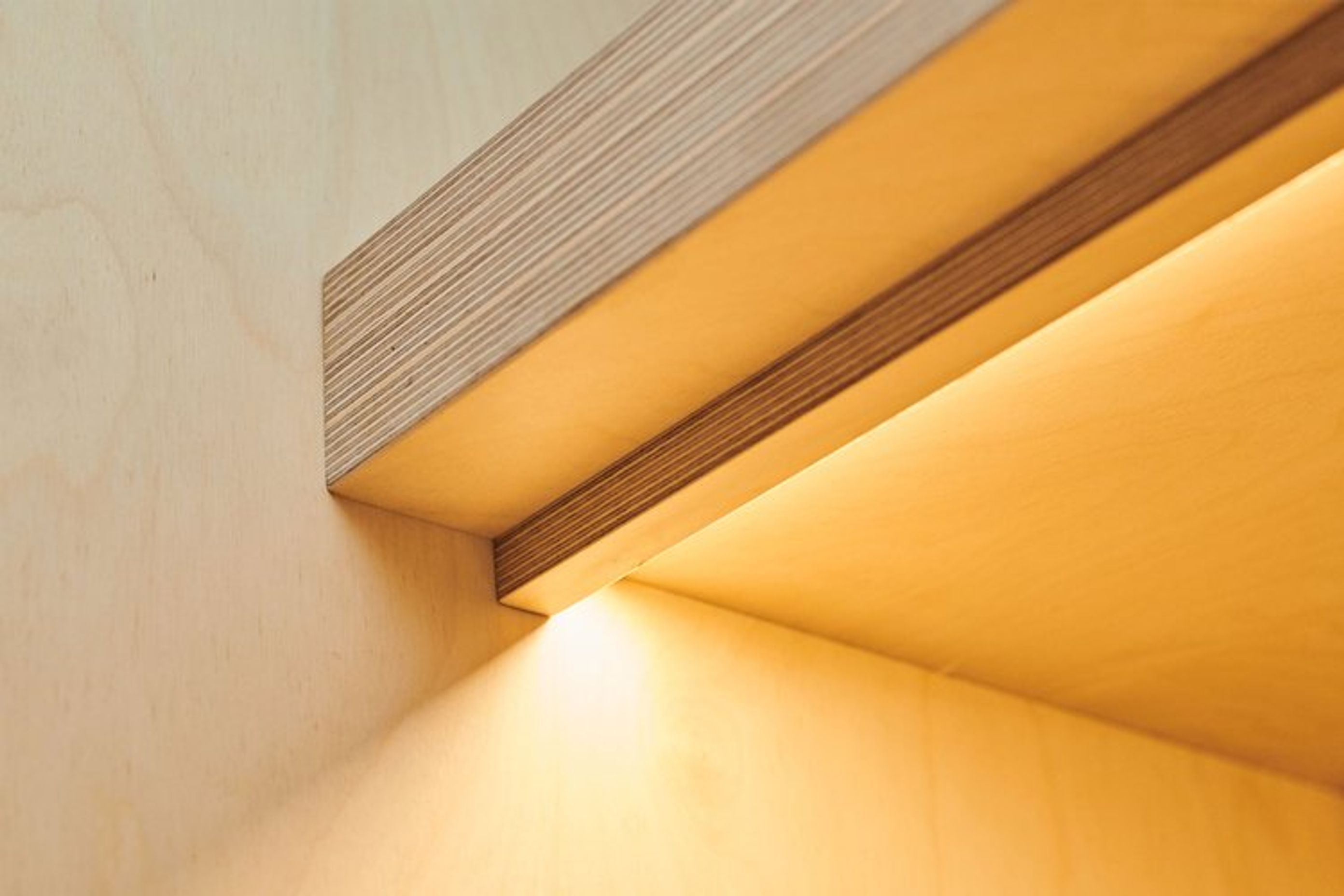 Laminated plywood shelving is lined with LED strip lighting to illuminate the bench top area beneath.