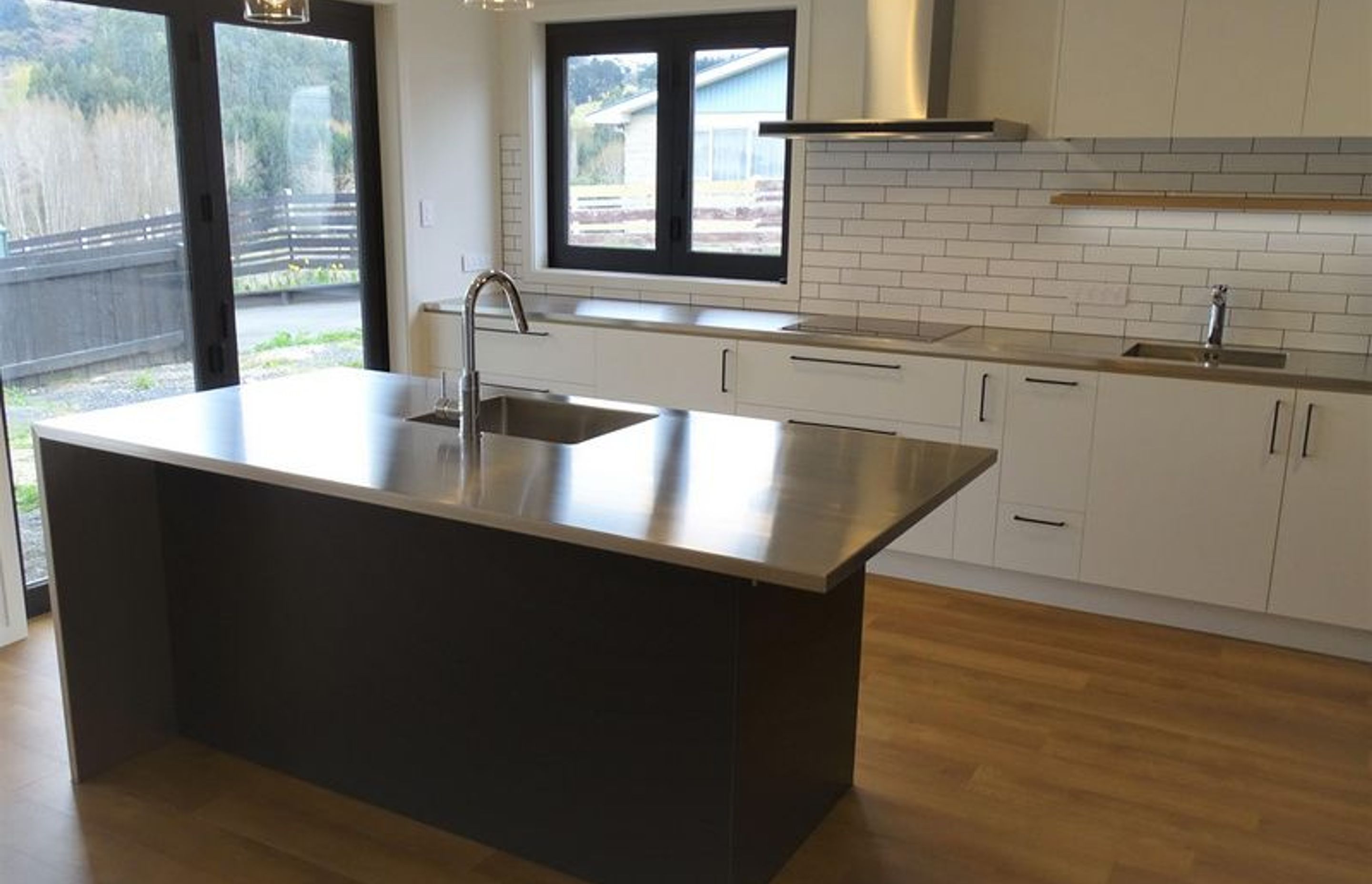 Modern kitchen merging white and black with stainless steel fittings